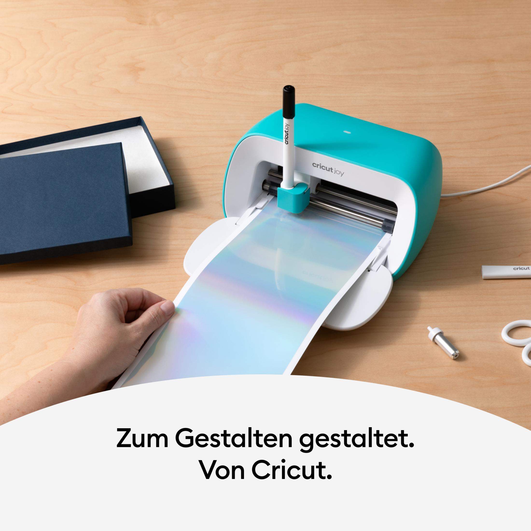 Cricut Joy Maschine mit Materialien und Hand bei der Benutzung.