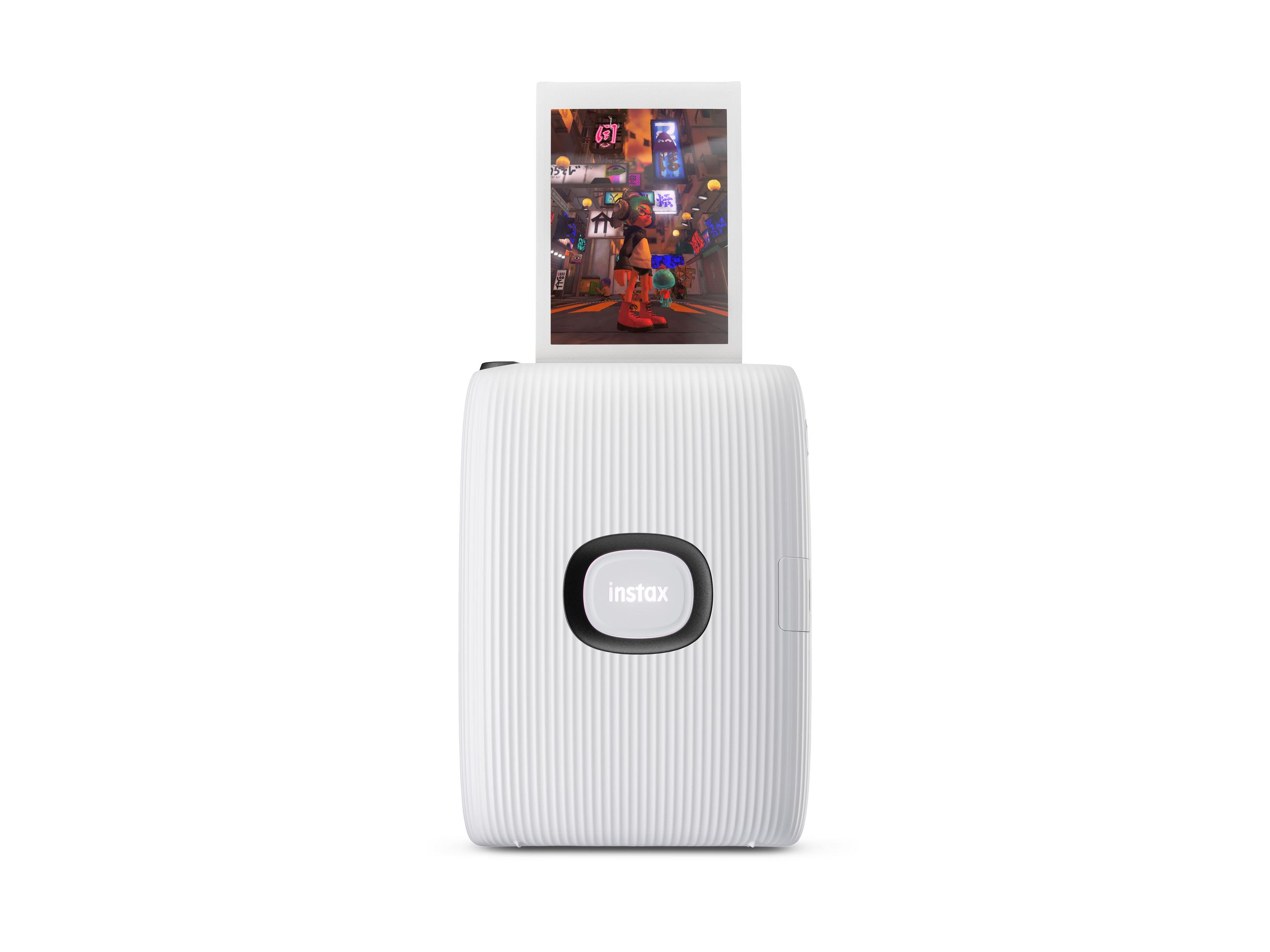 Weißer Instax-Drucker mit herauskommendem Foto. Das Foto zeigt ein Gebäude mit Menschen.