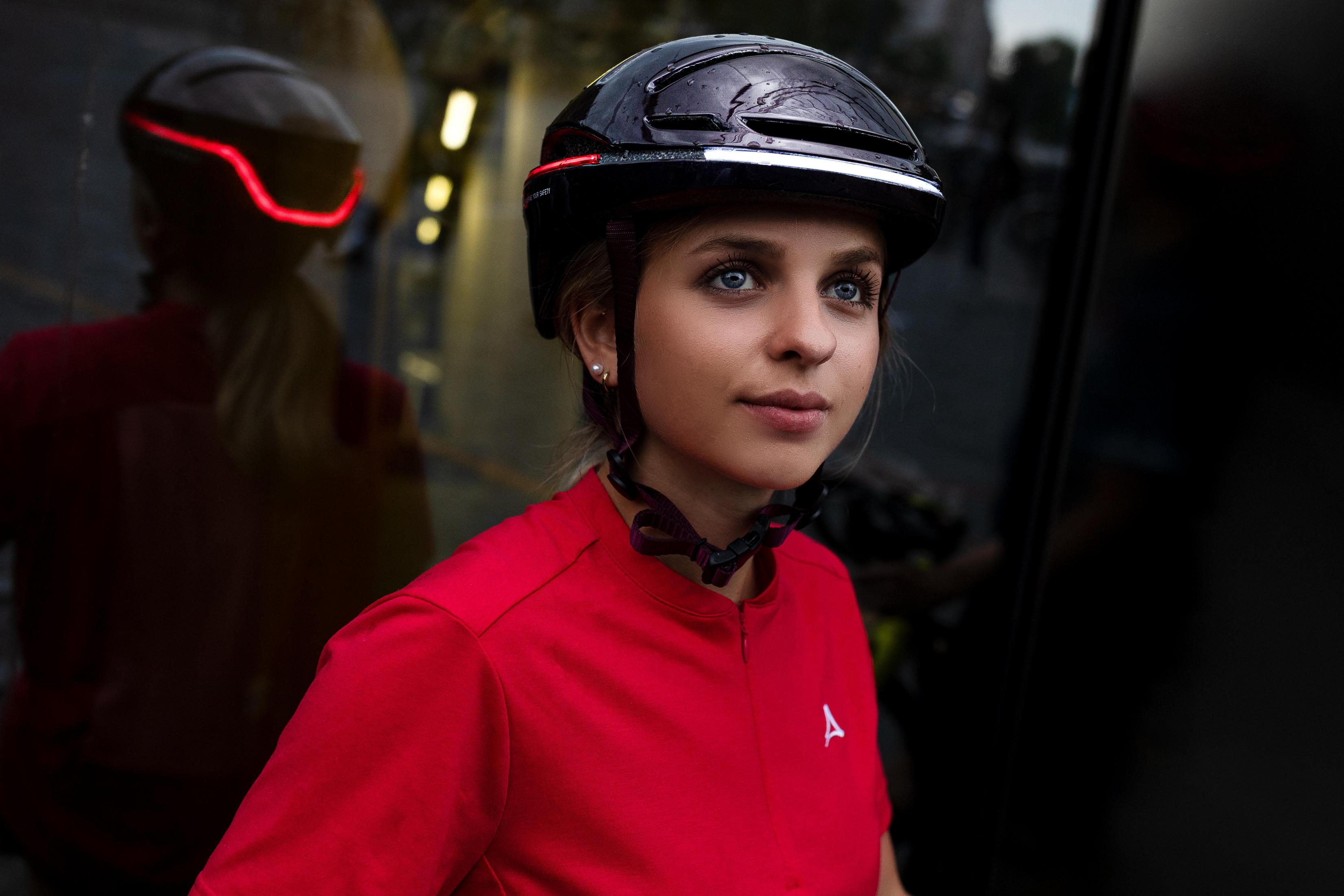 Donna con maglia da ciclismo rossa e casco con luce rossa.