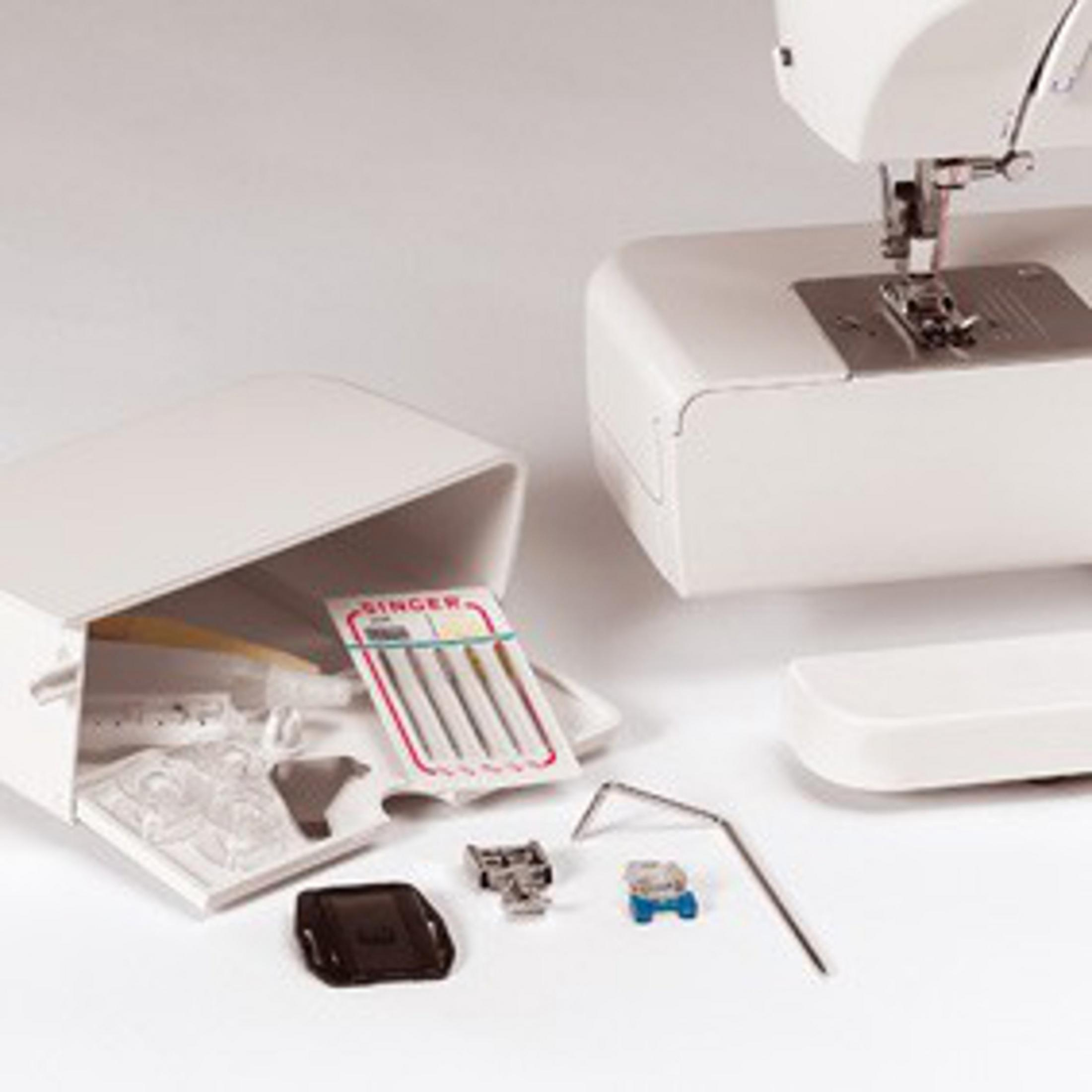 Primer plano de una máquina de coser con accesorios, incluyendo una caja, agujas y otras partes.