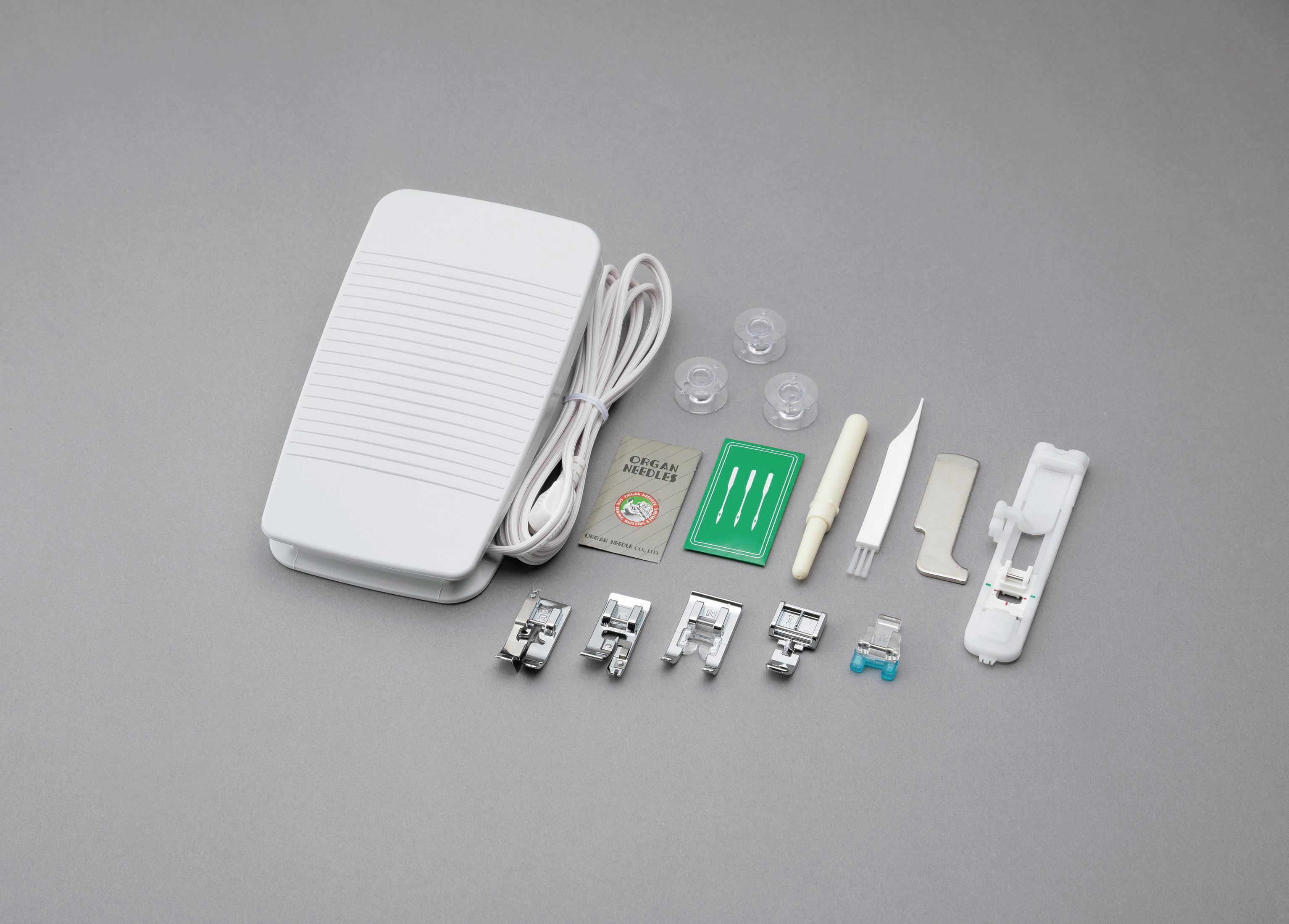 Pedał maszyny do szycia, akcesoria i igły na szarej powierzchni.