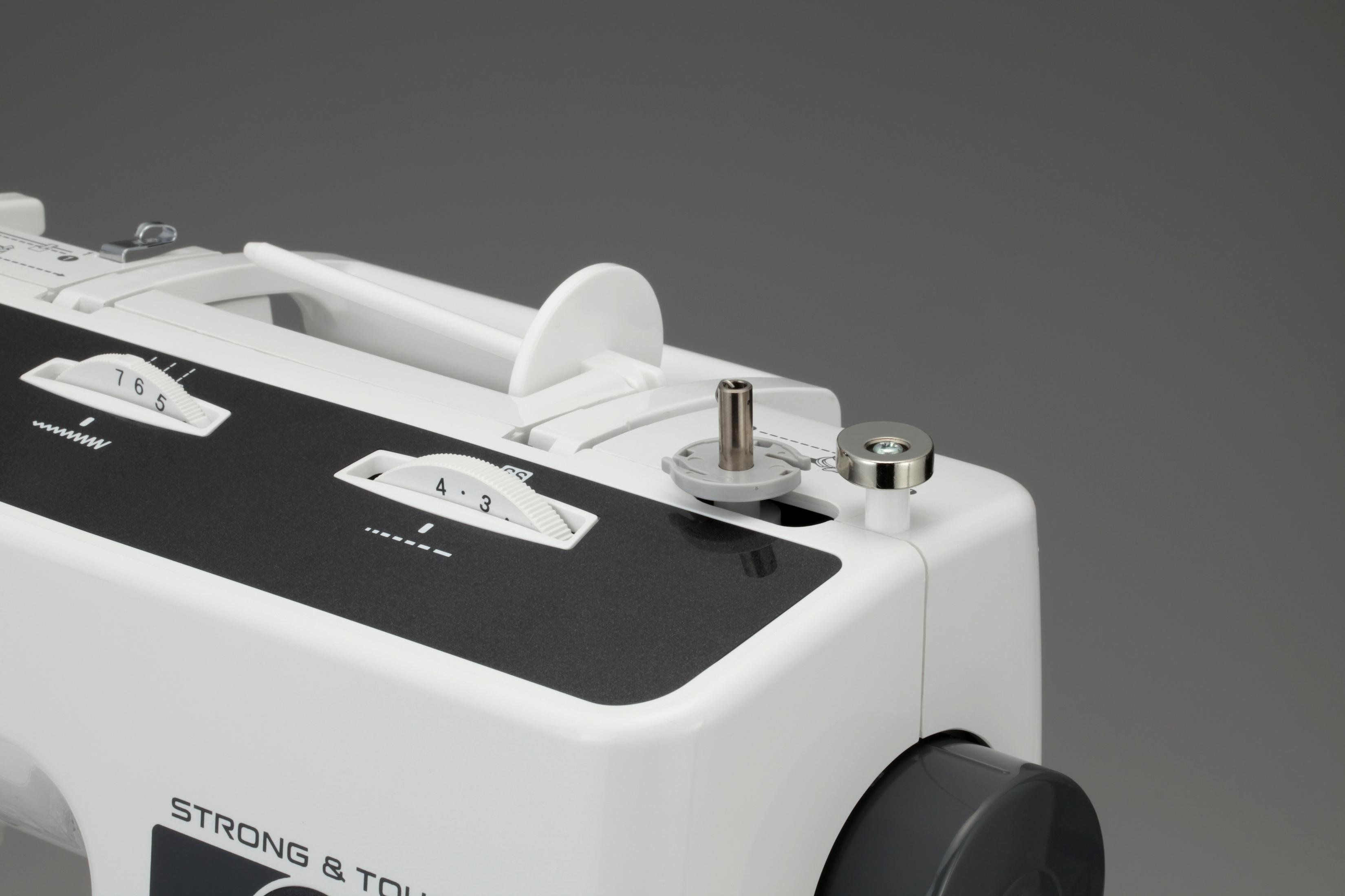 Zbliżenie na elementy maszyny do szycia, pokazujące tarcze i obszar szpulki.