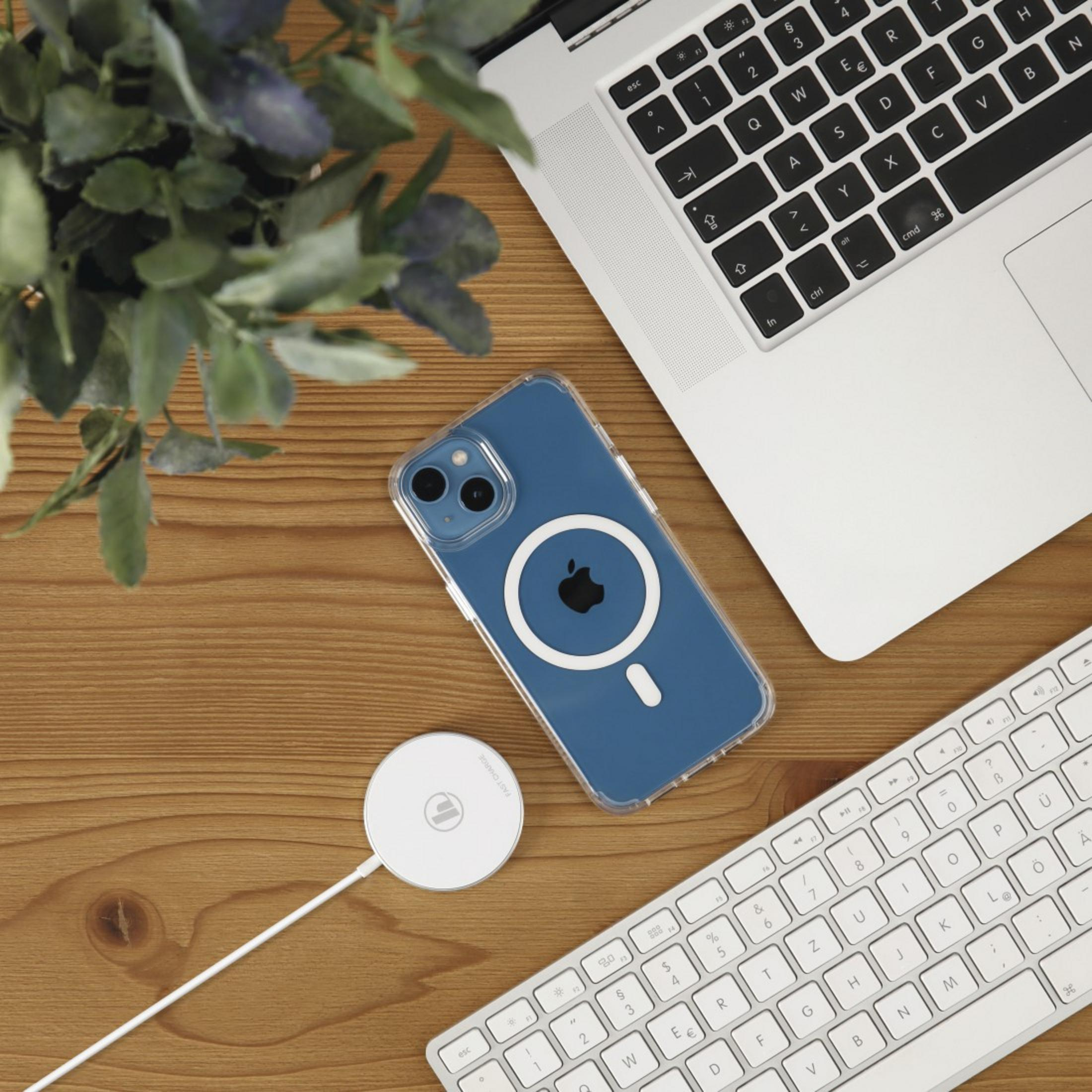 Smartfon na drewnianym stole z laptopem, klawiaturą i ładowarką.