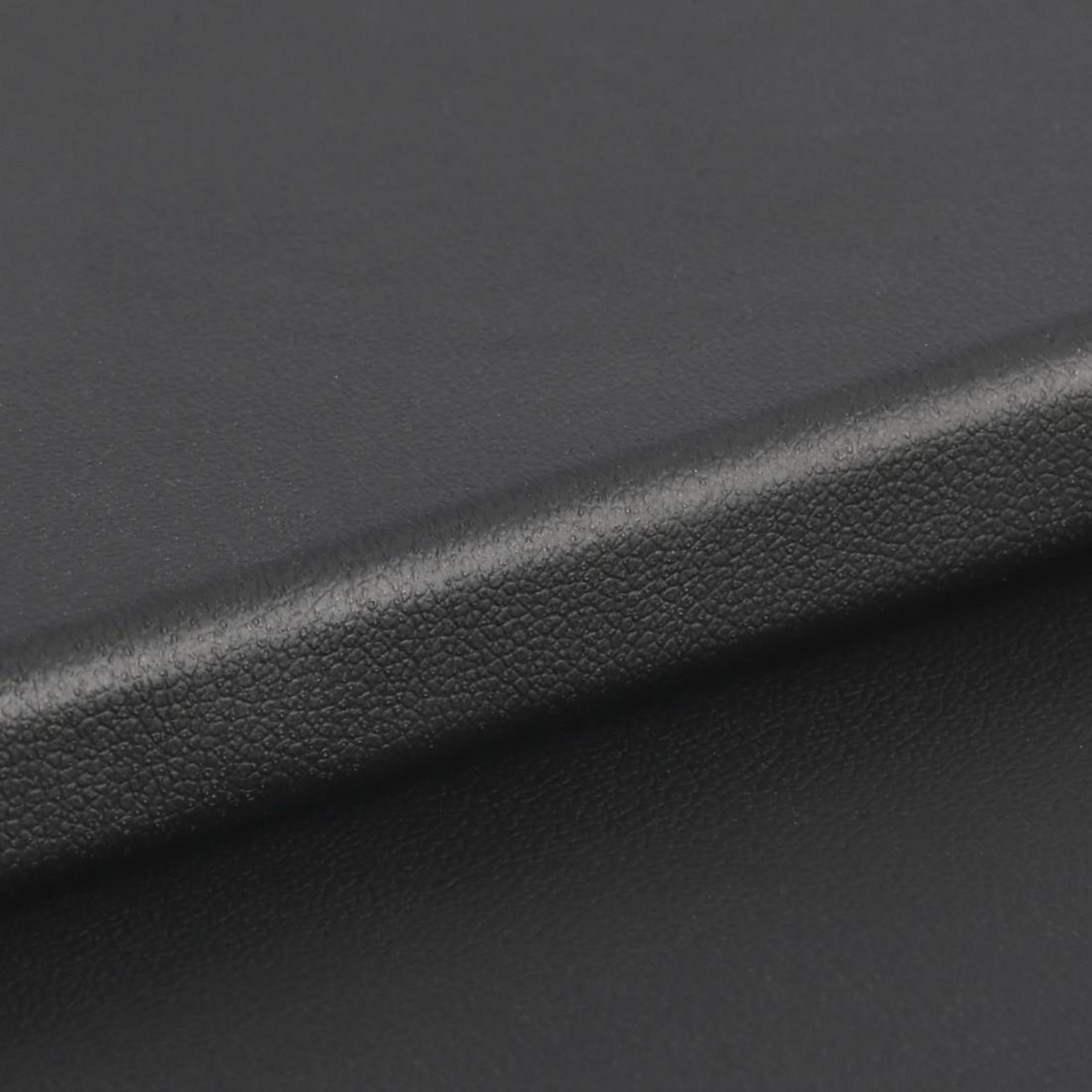 Zbliżenie czarnej skórzanej powierzchni z subtelną fakturą i lekkim zakrzywieniem.