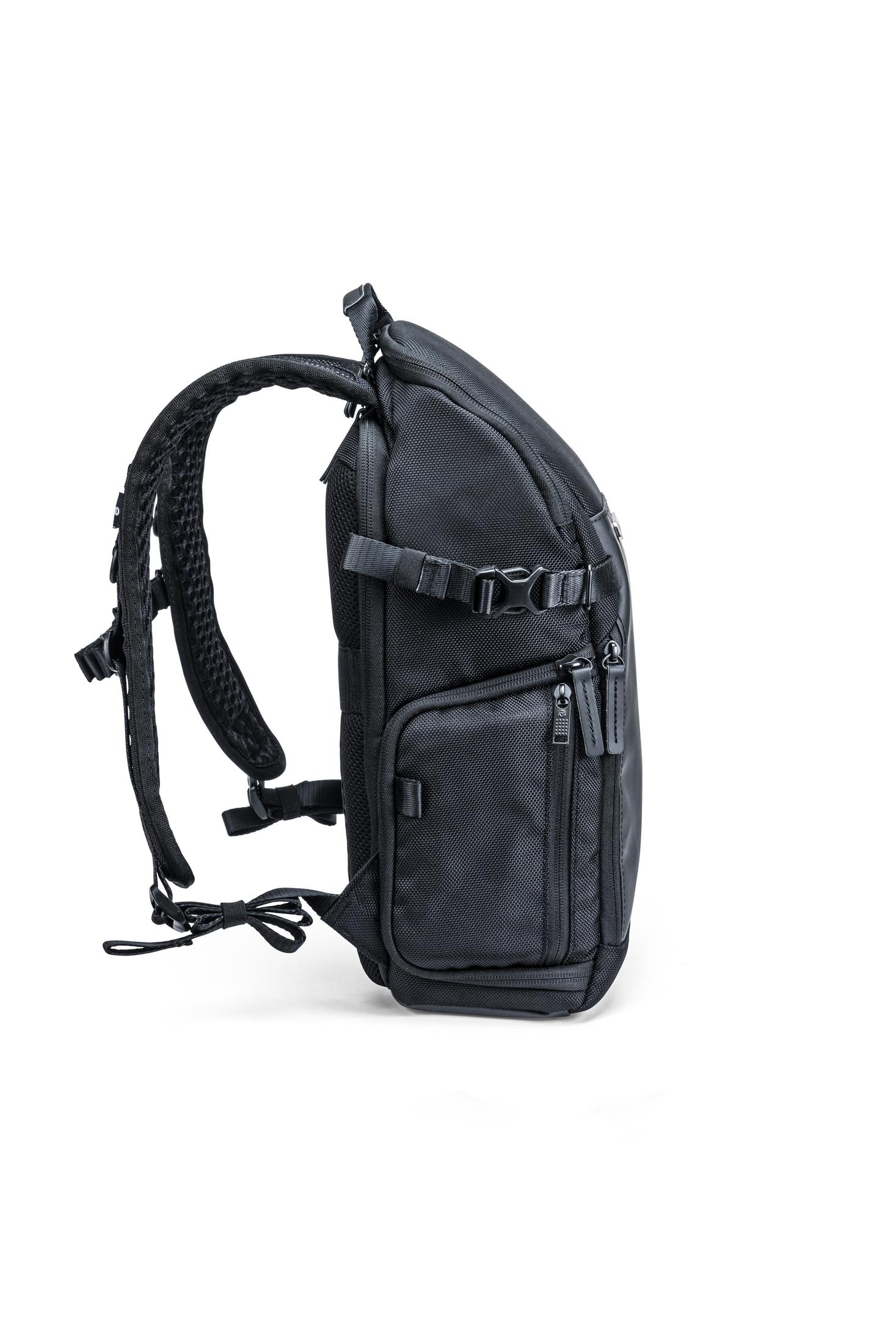 Una mochila negra con muchas correas y compartimentos, vista lateral.