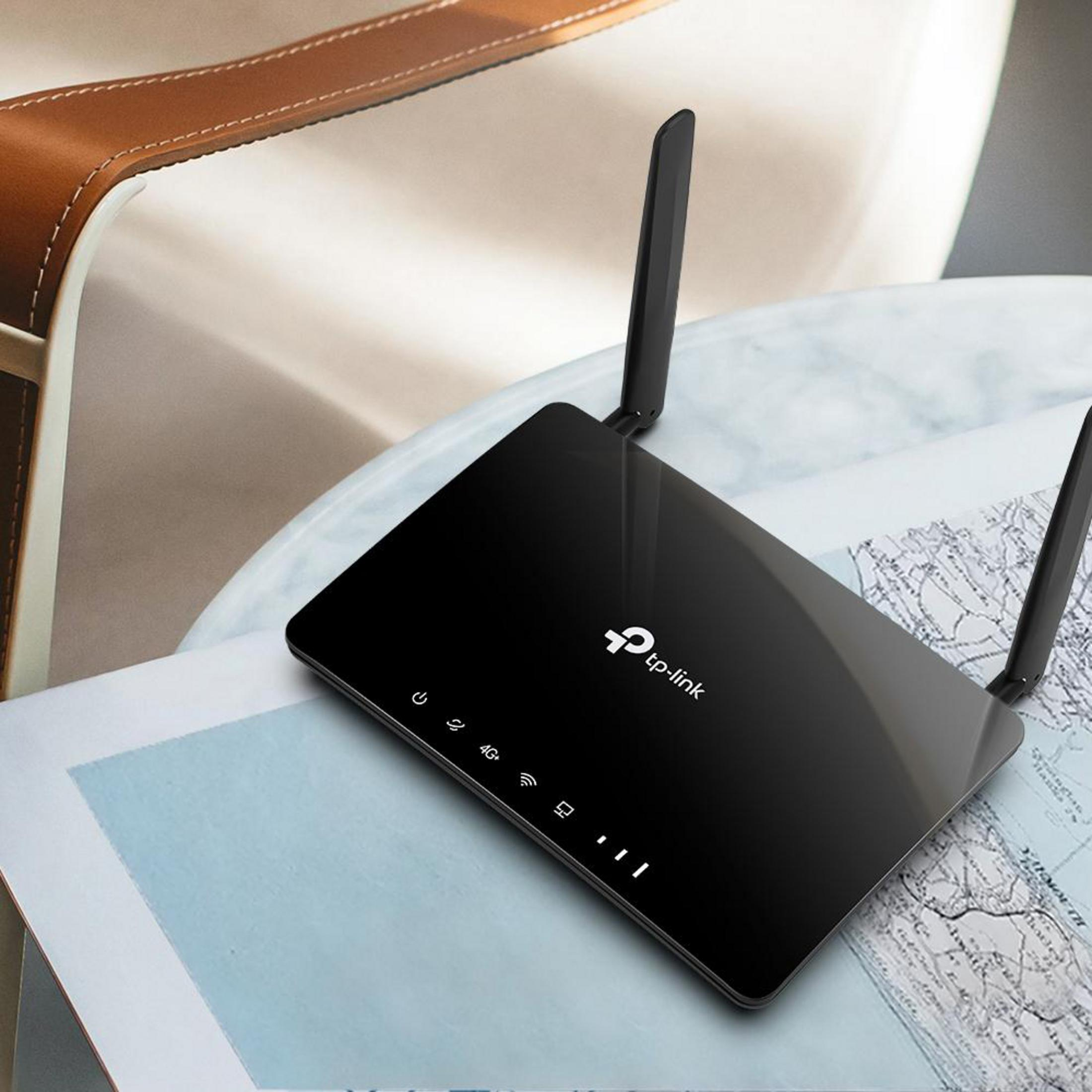 Zwarte TP-Link router met antennes op een tafel met een kaart. De achtergrond is wazig.