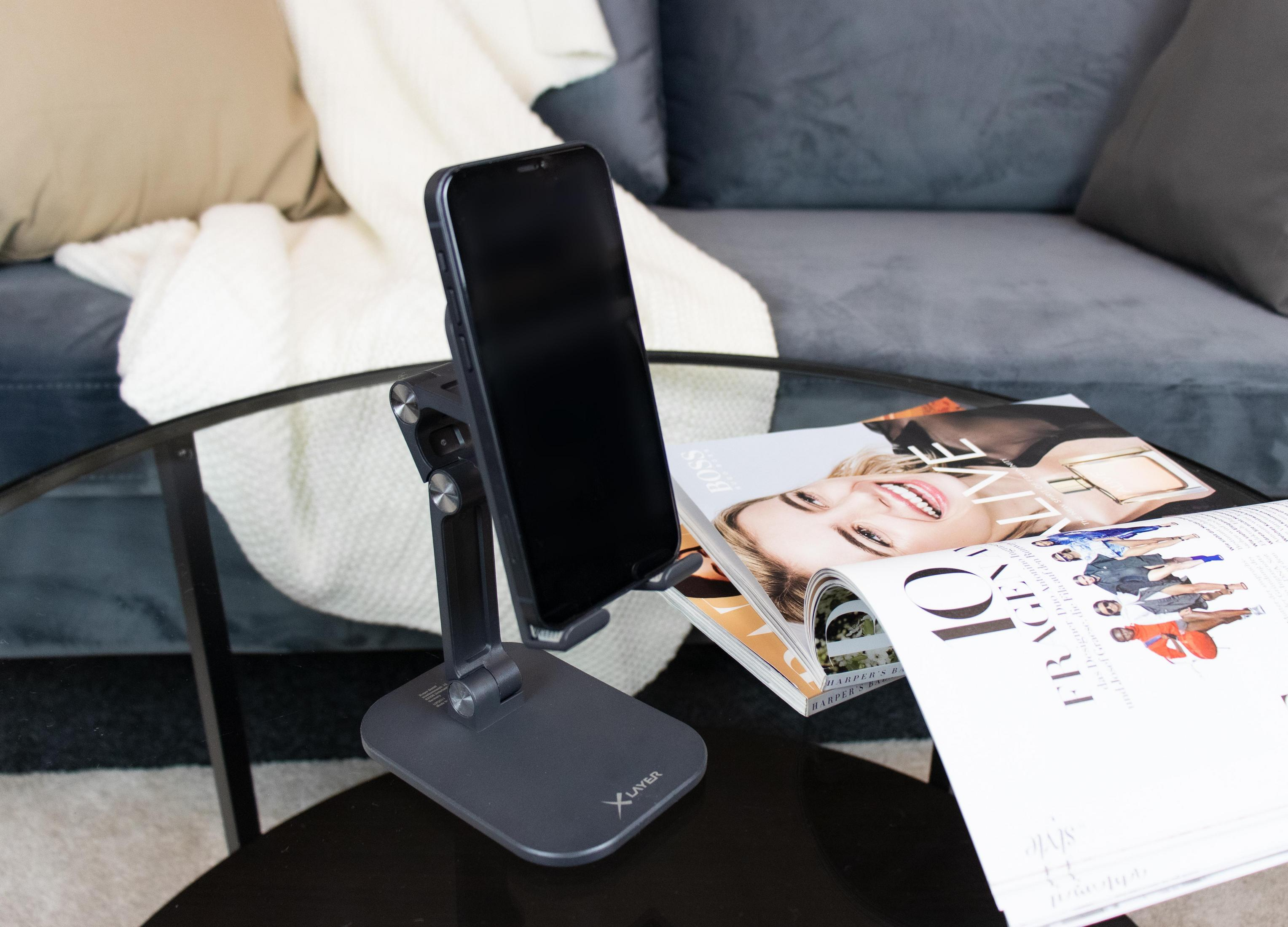 Telefon auf Ständer, Zeitschrift auf Tisch. Sofa und Teppich im Hintergrund.