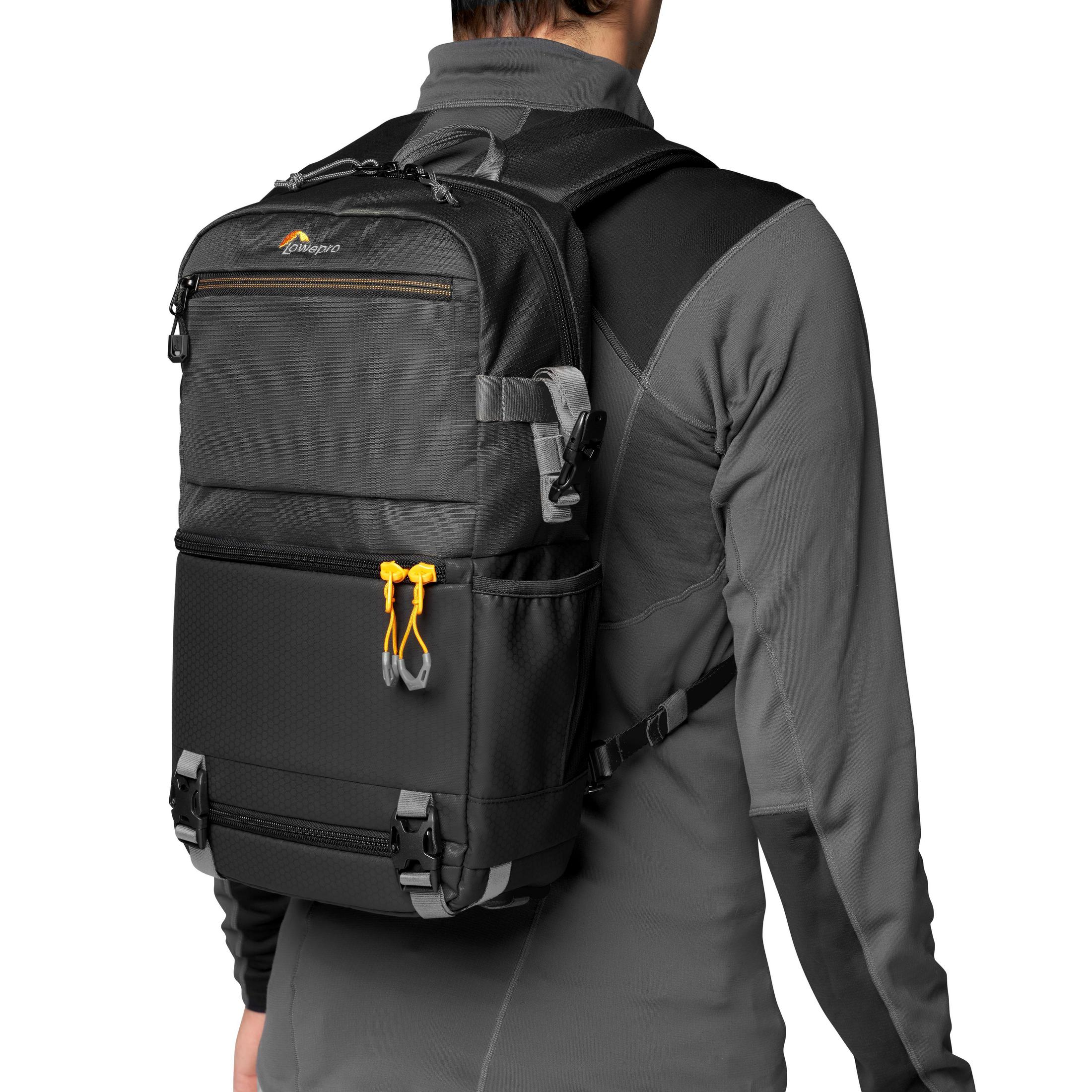 Schwarzer Lowepro-Kamera-Rucksack auf dem Rücken einer Person, graue Details und gelbe Akzente.