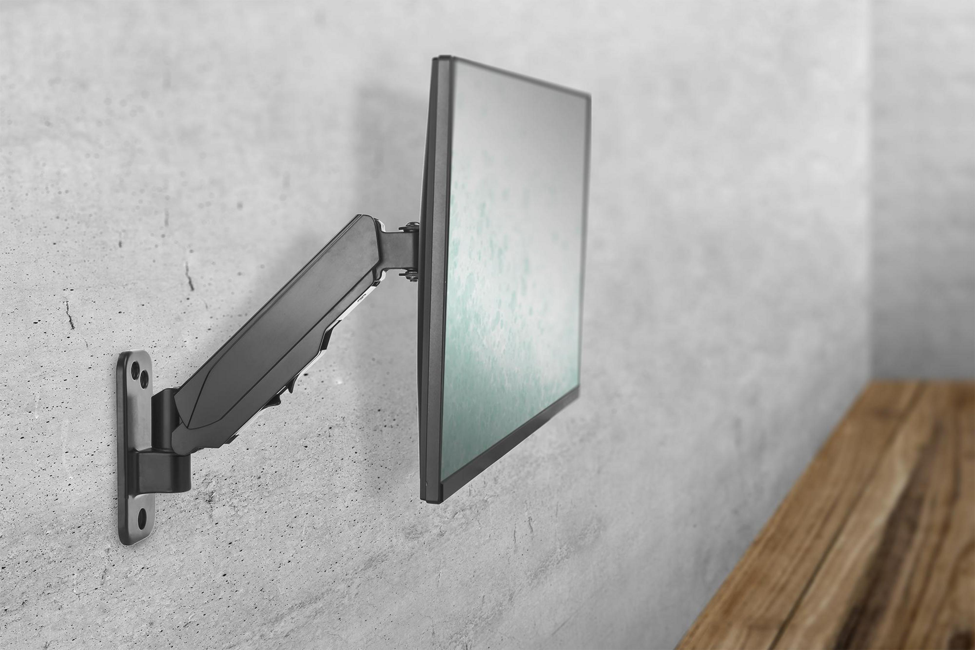 Ein Monitor, der mit einem schwarzen Arm an einer Wand befestigt ist. Die Wand ist grau, und eine Holzoberfläche ist in der Ecke.