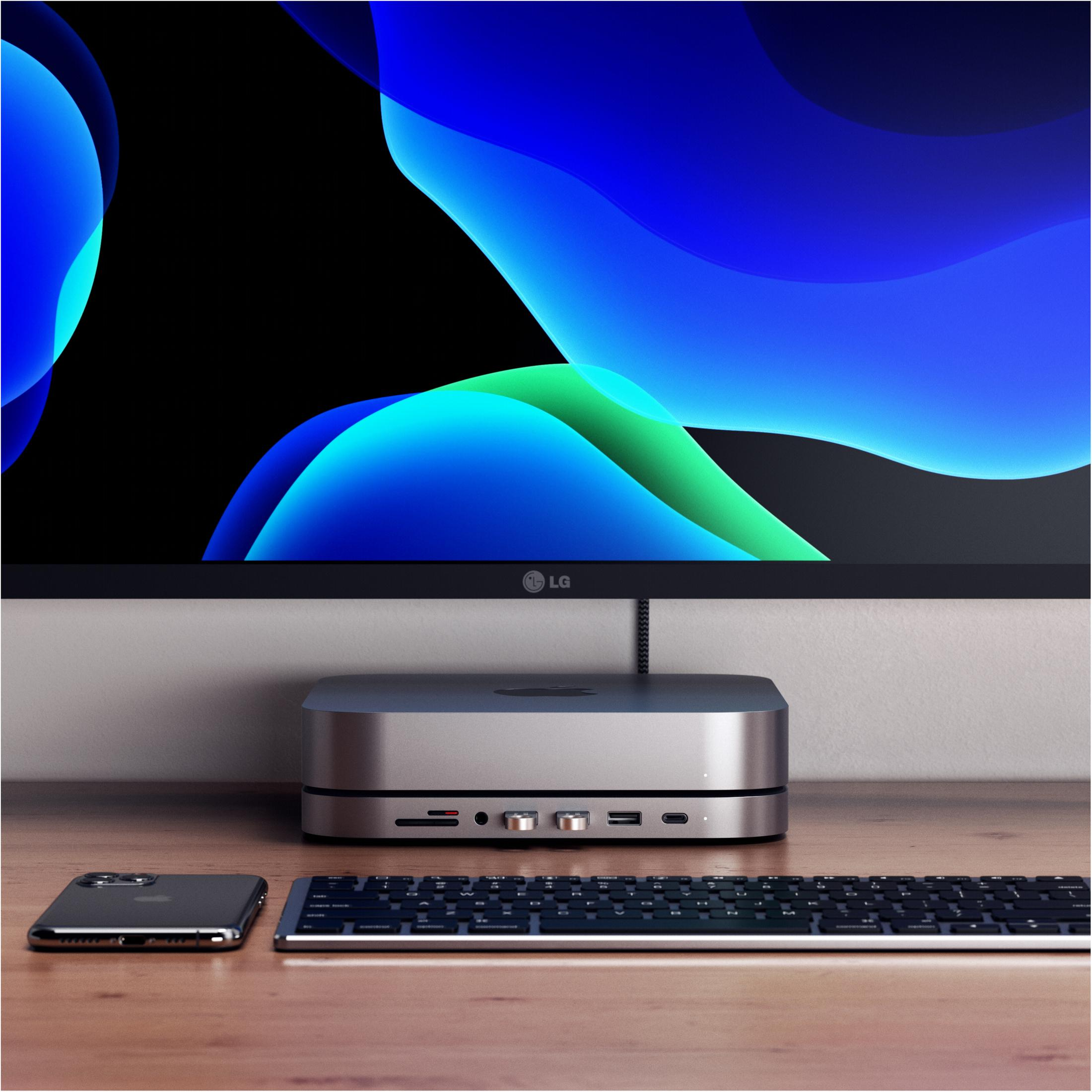 Ein silberner Hub mit Monitor, Telefon und Tastatur auf einem Holzschreibtisch.