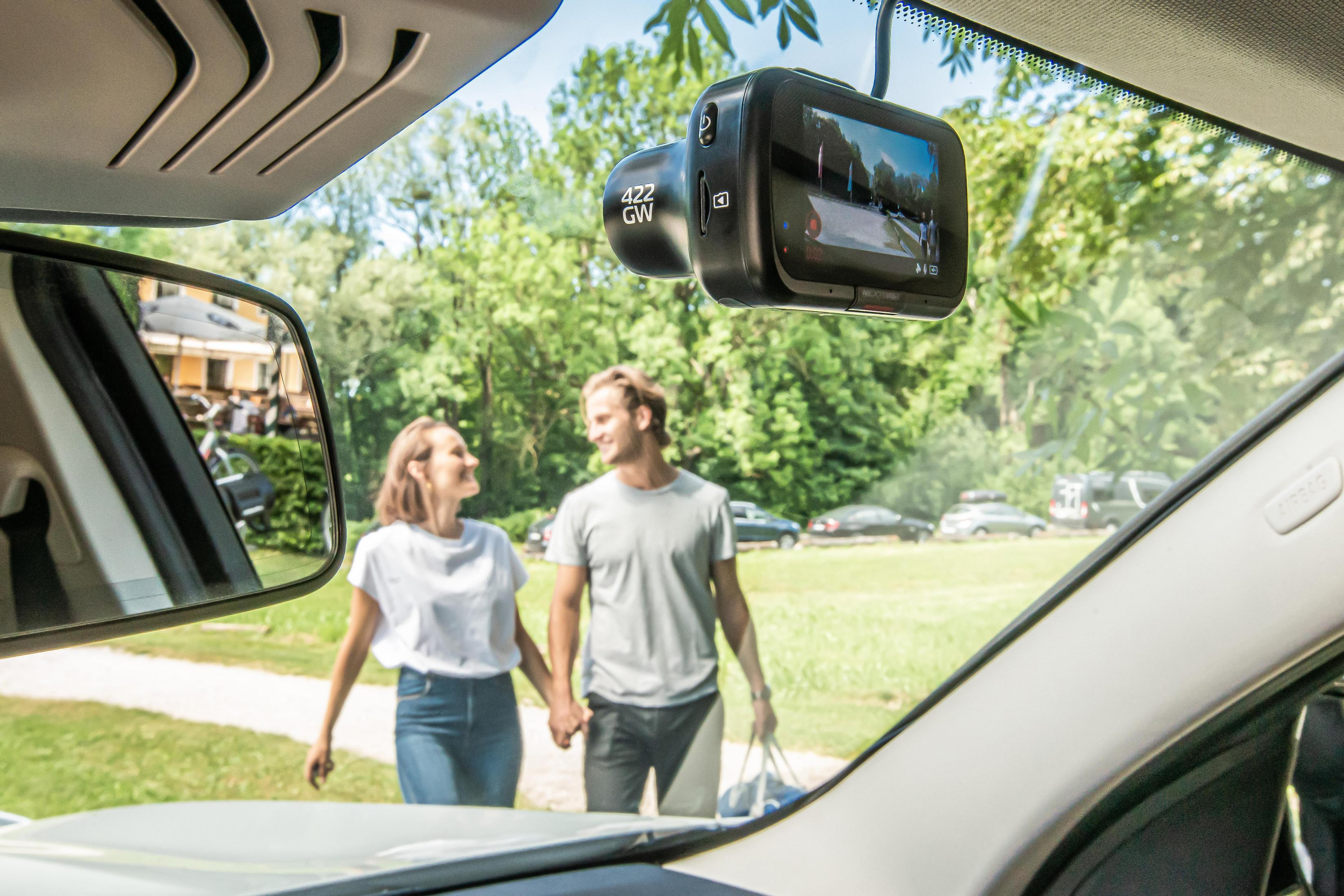Im Auto zeigt eine Dashcam eine Straße. Ein Paar hält Händchen und geht in einen Park.