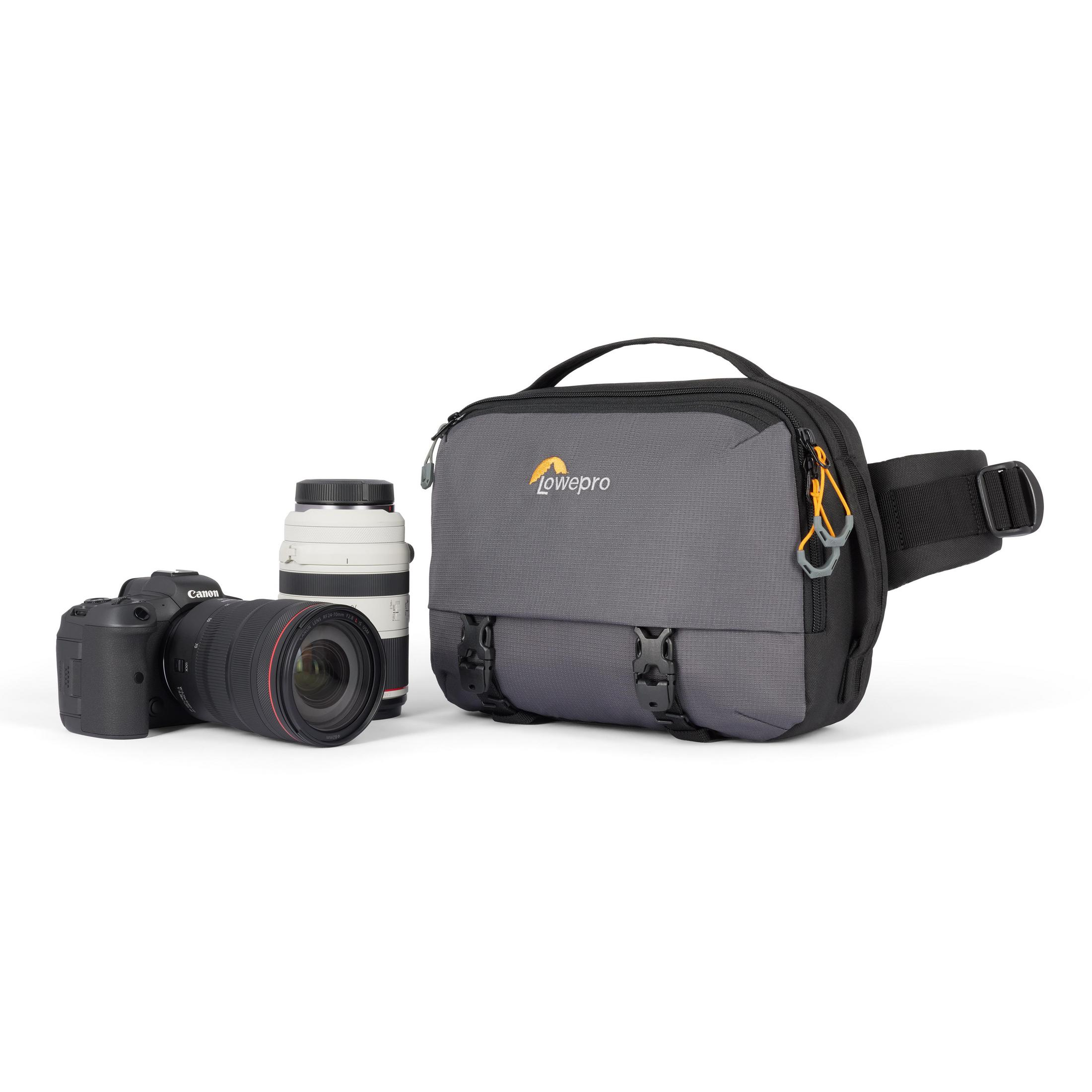 Una borsa per fotocamera Lowepro grigia con una fotocamera Canon e un obiettivo accanto su una superficie bianca.