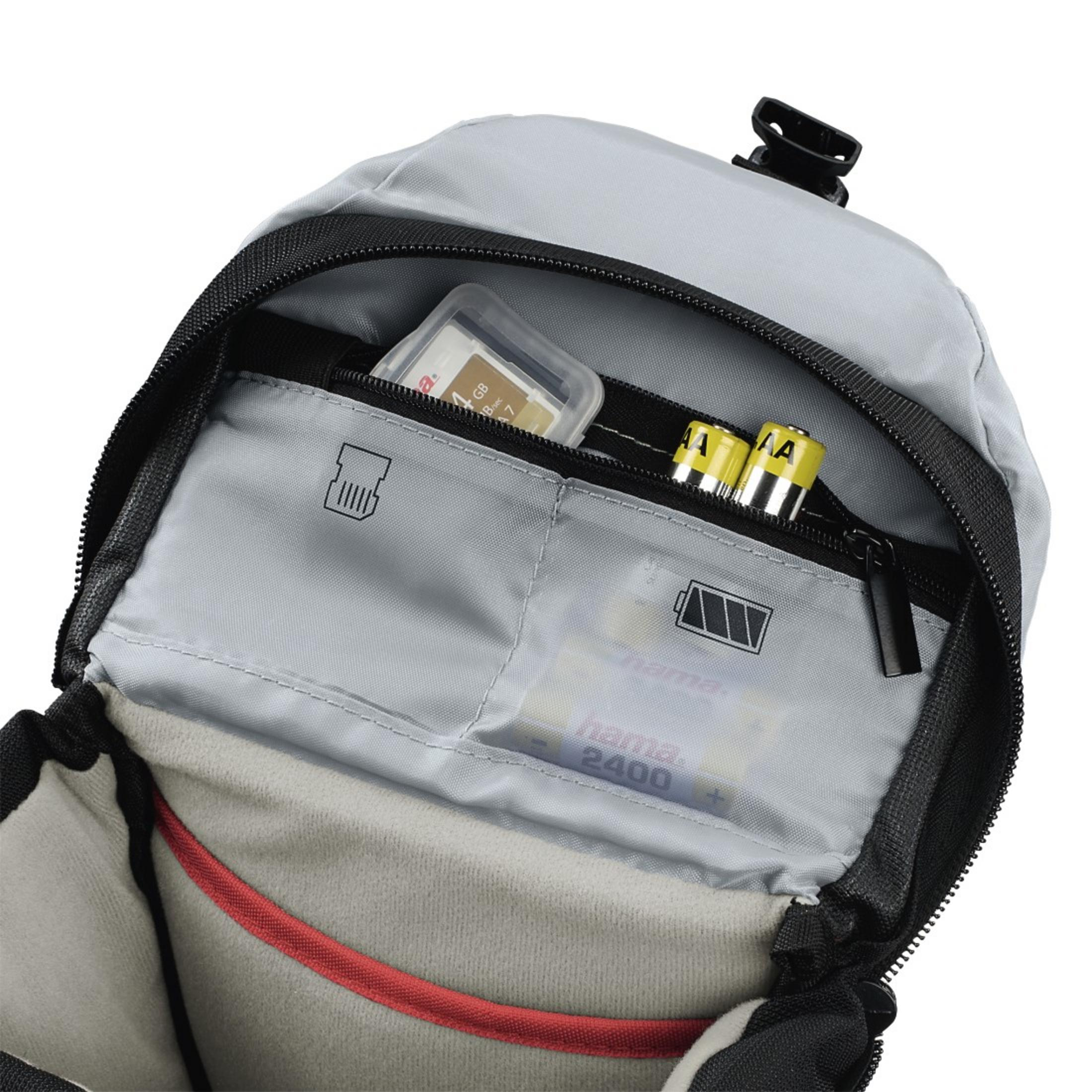Offenes graues Rucksackinnere mit einer SD-Karte und Batterien in den Taschen. Ein Batteriesymbol ist sichtbar.
