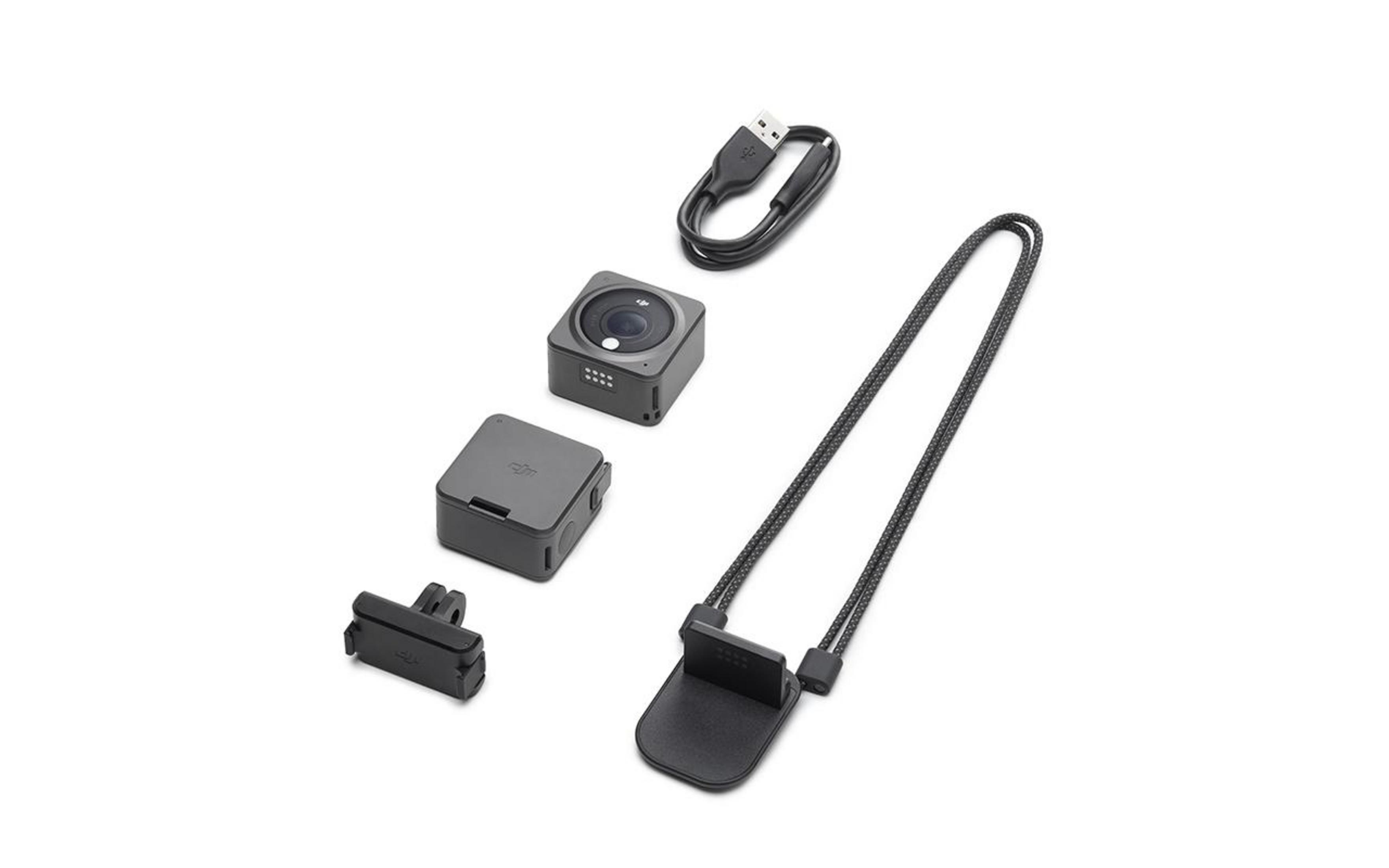 Kamera, Hülle, USB-Kabel und Lanyard mit Halterung, alle grau, auf weißer Oberfläche angeordnet.