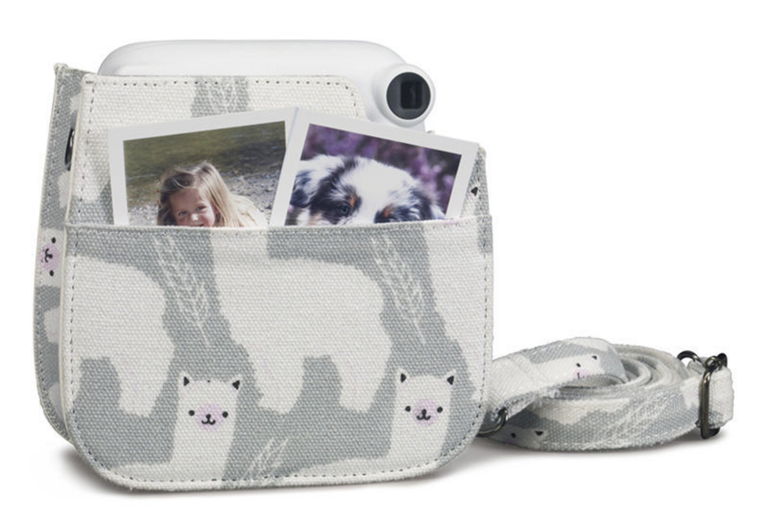 White camera in a gray case with a strap. Two photos are in the case pocket. Cute llama print.