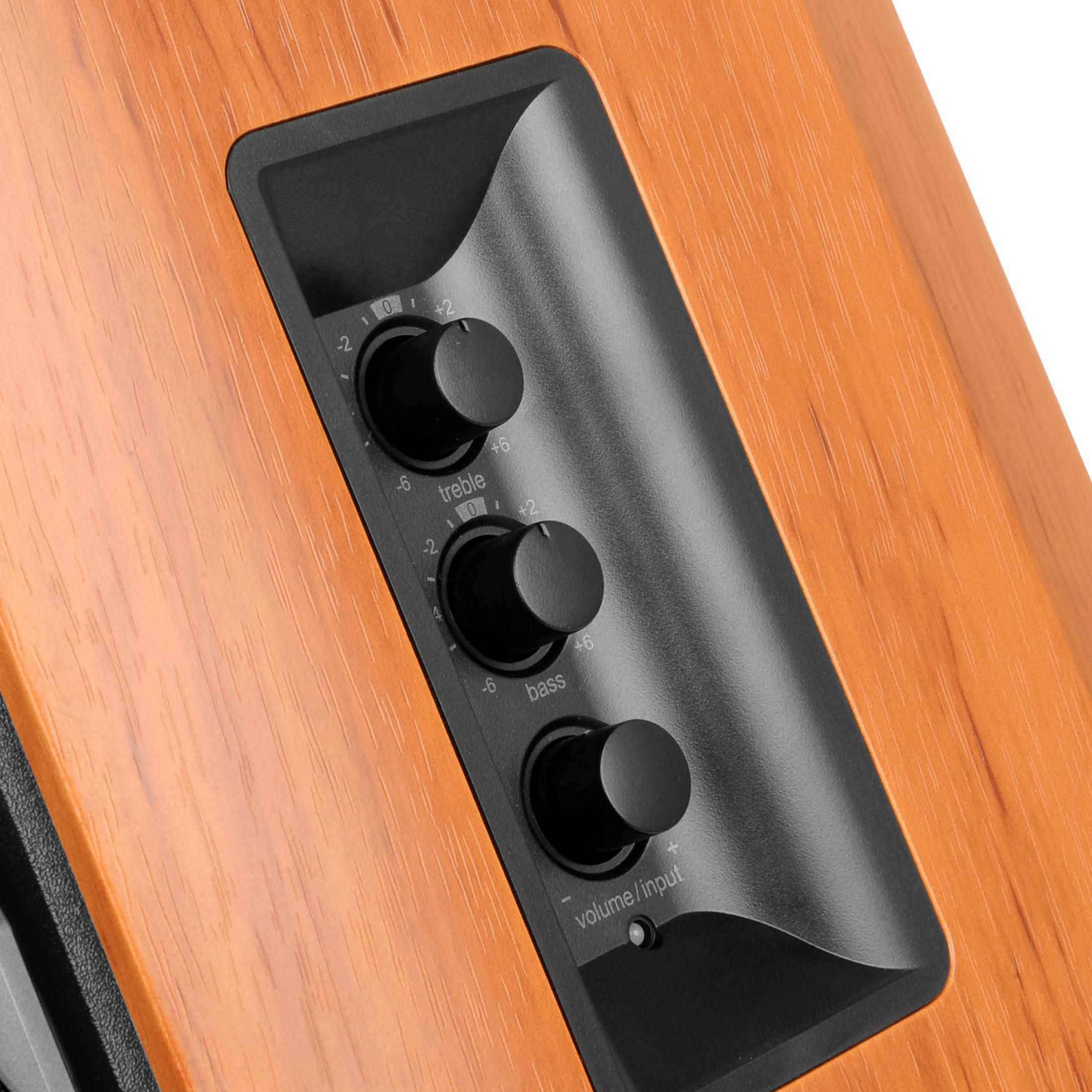 Primo piano di un pannello di controllo dell'altoparlante in legno. Tre manopole nere controllano alti, bassi e volume.