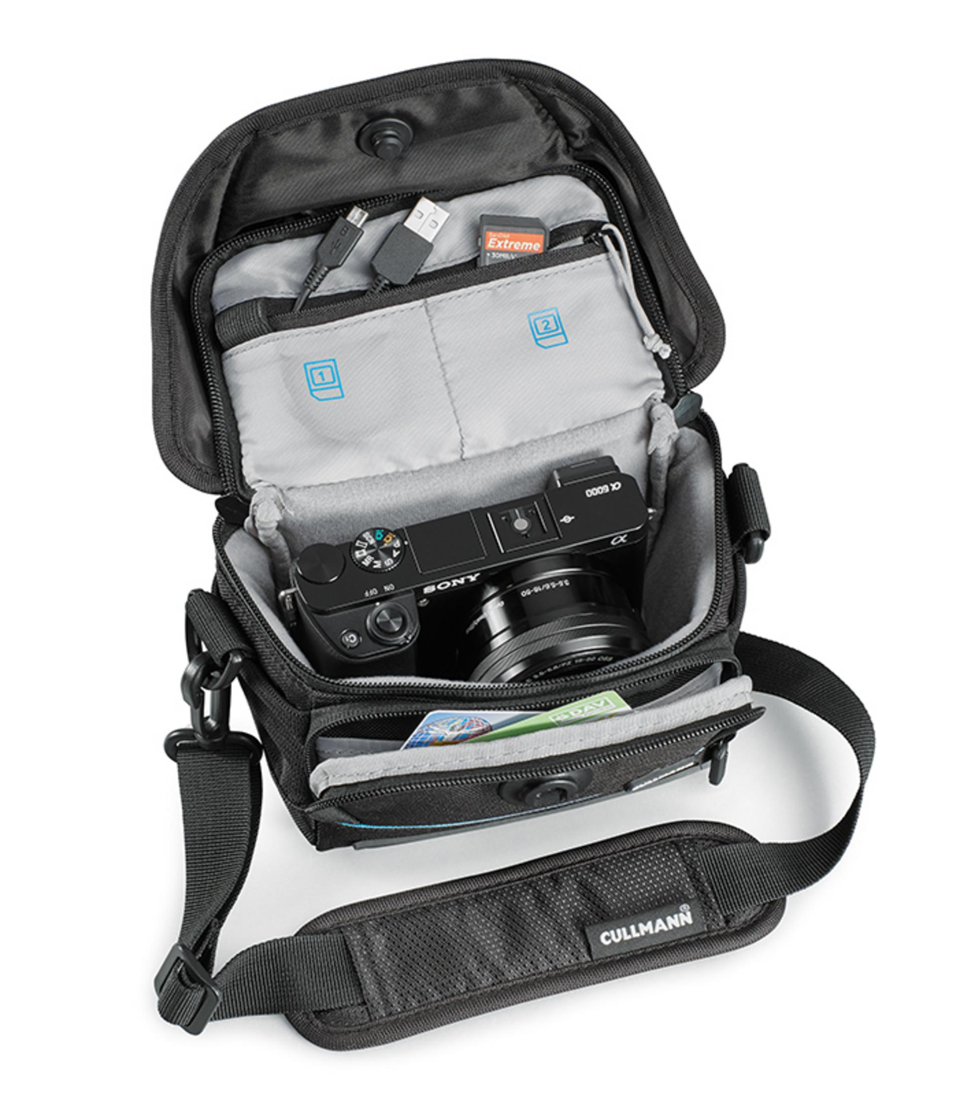 Geöffnete Kameratasche mit Kamera, SD-Karte und USB-Kabel darin.