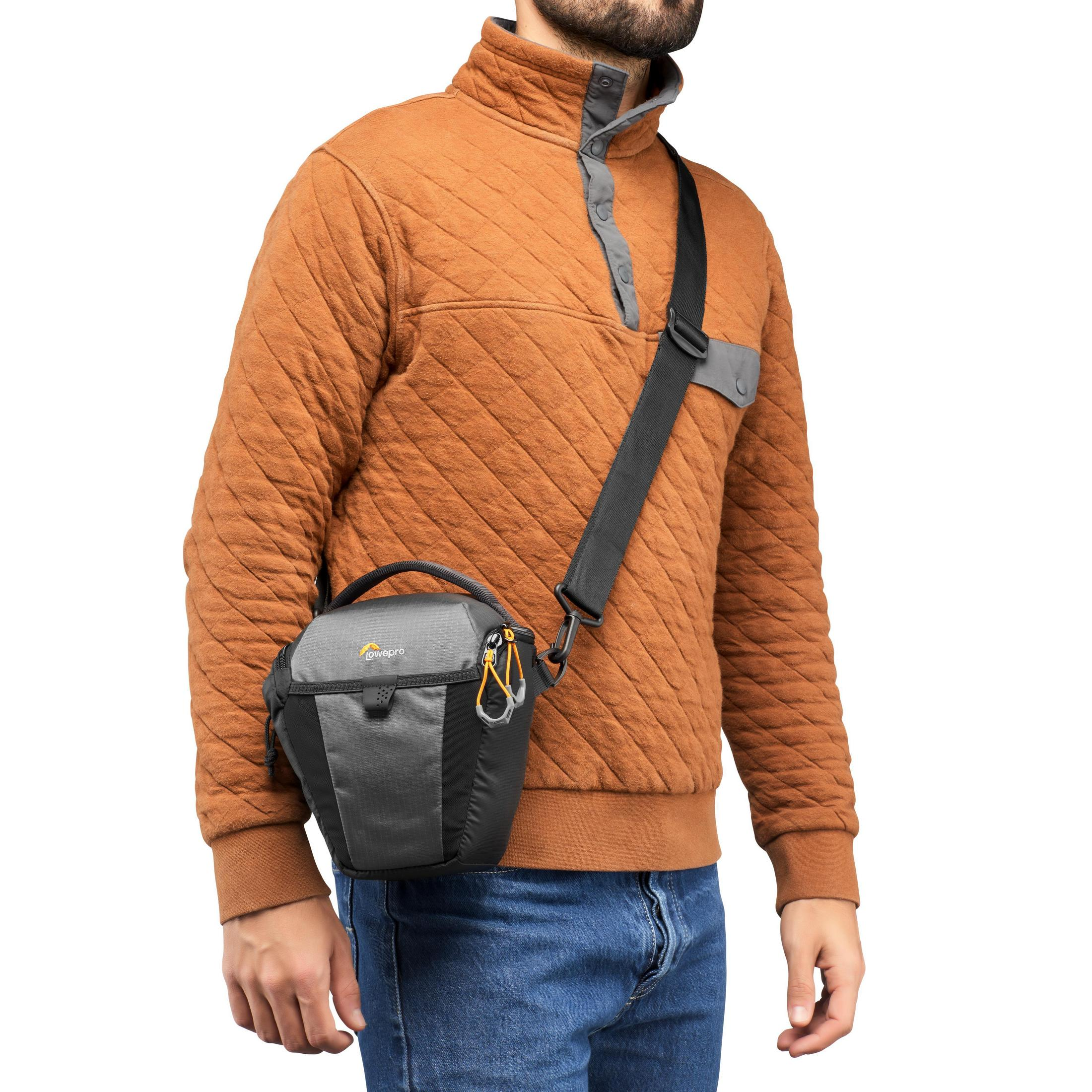 Mann in braunem Pullover mit Kameratasche über dem Körper.