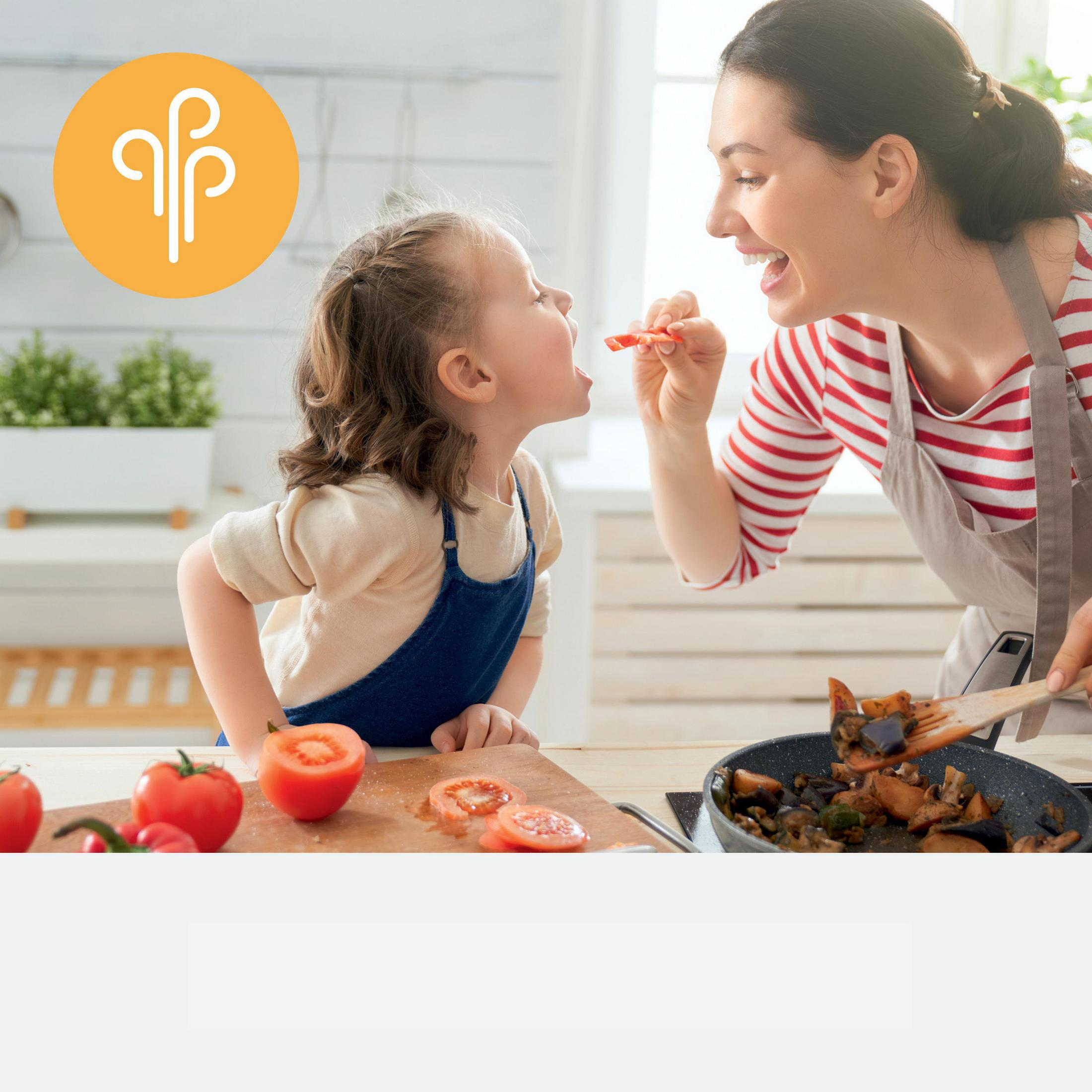 Matka karmi dziecko w kuchni pomidorami i patelnią na kuchence.