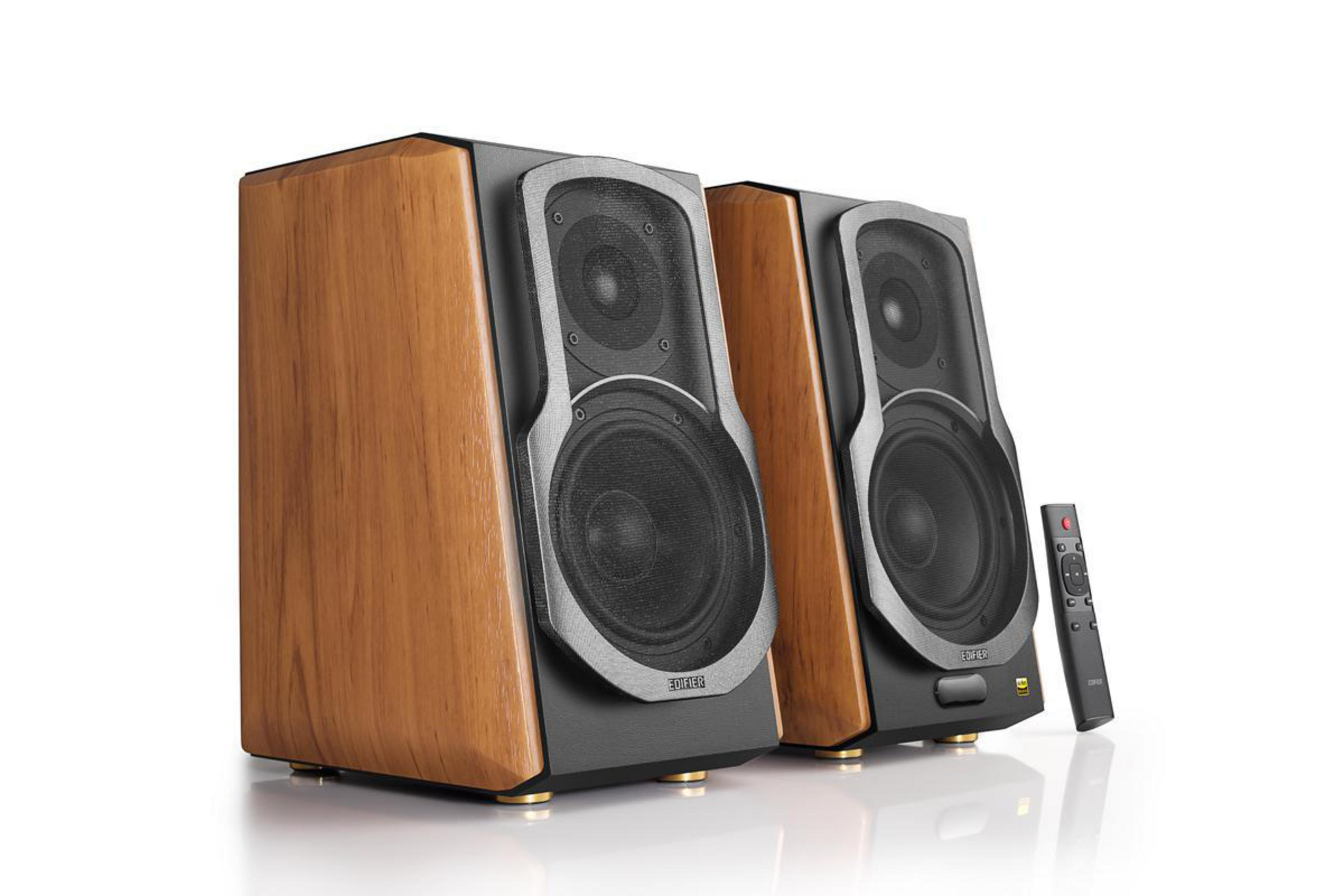 Dwa drewniane głośniki z czarnymi frontami i pilotem.