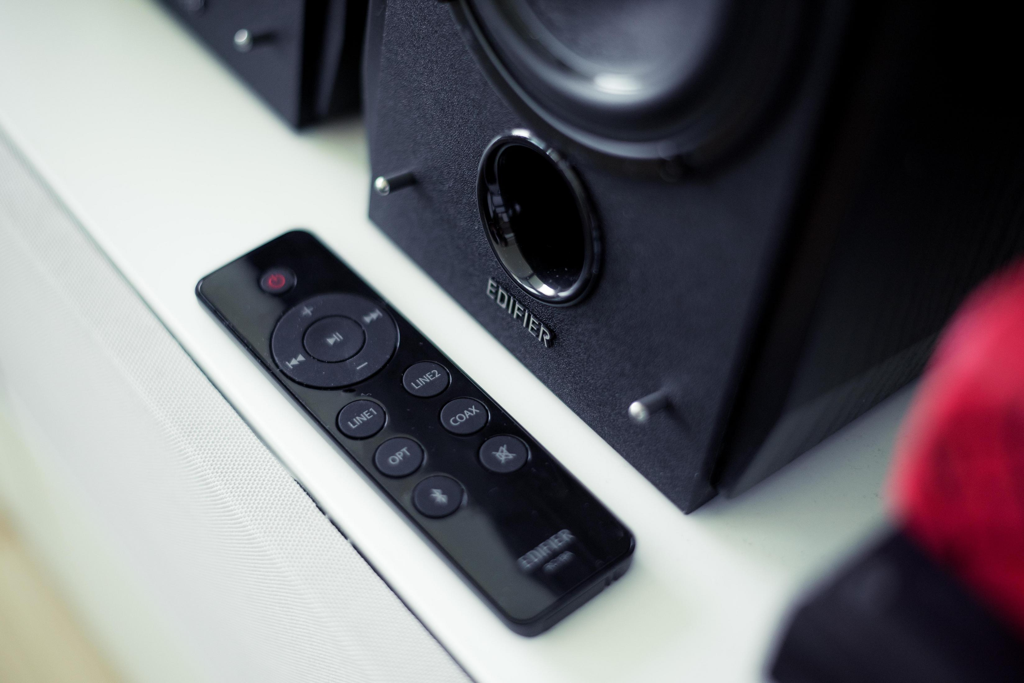 Czarny pilot na białej powierzchni obok czarnego głośnika.