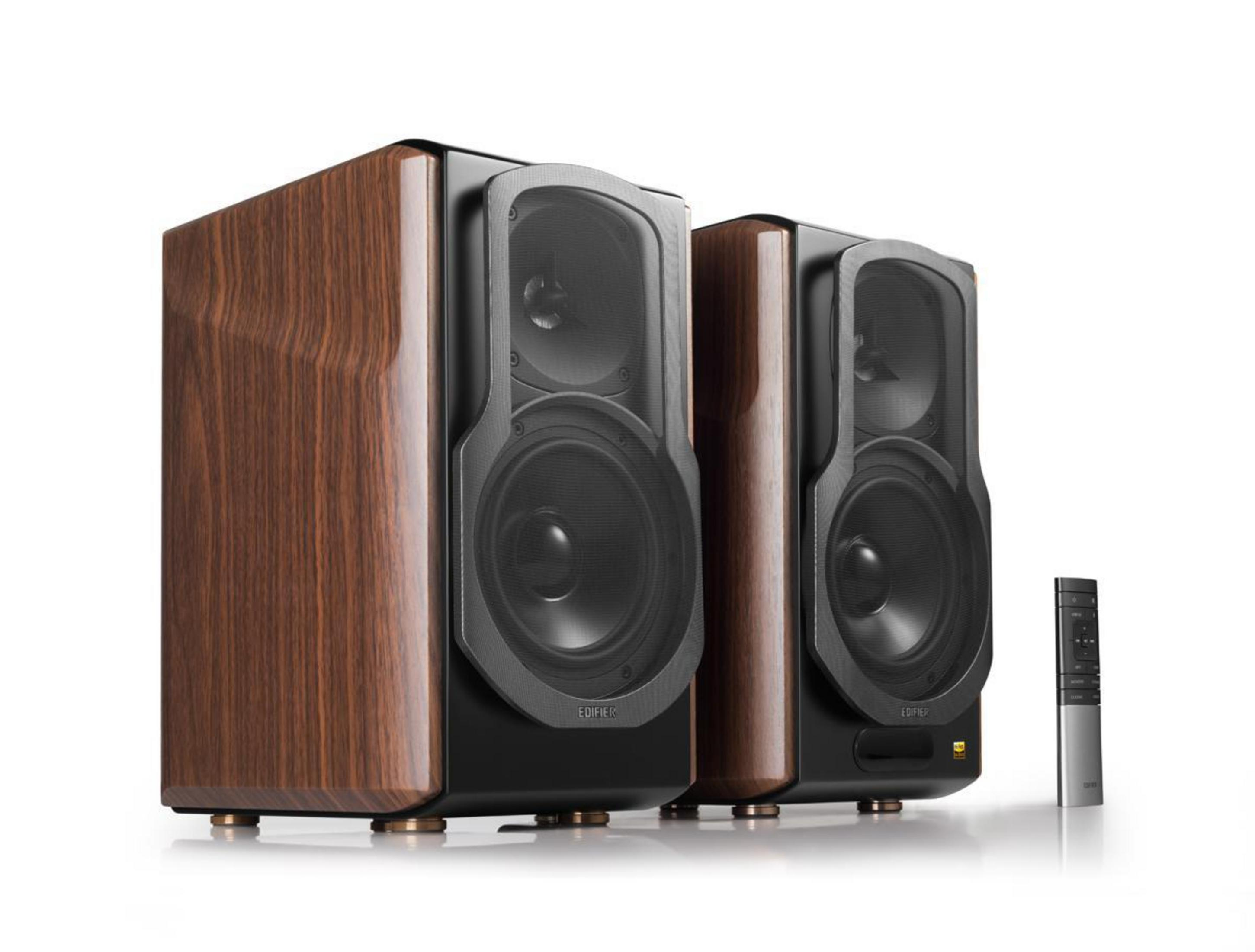 Dwa drewniane głośniki z wykończeniem z ciemnego drewna, czarnym przodem i srebrnym pilotem na białym tle.