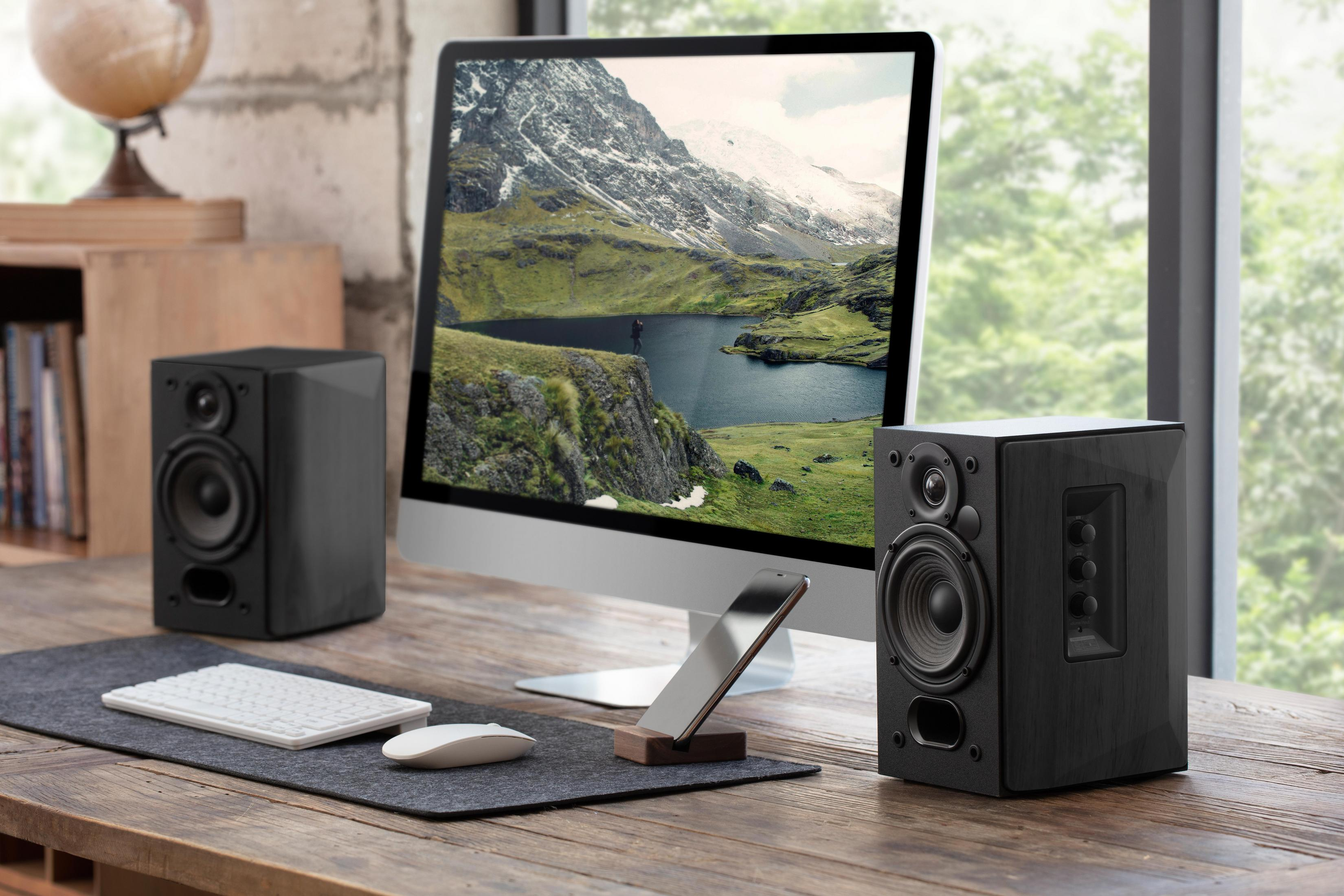 Scrivania con computer, altoparlanti e accessori. Finestra sullo sfondo.