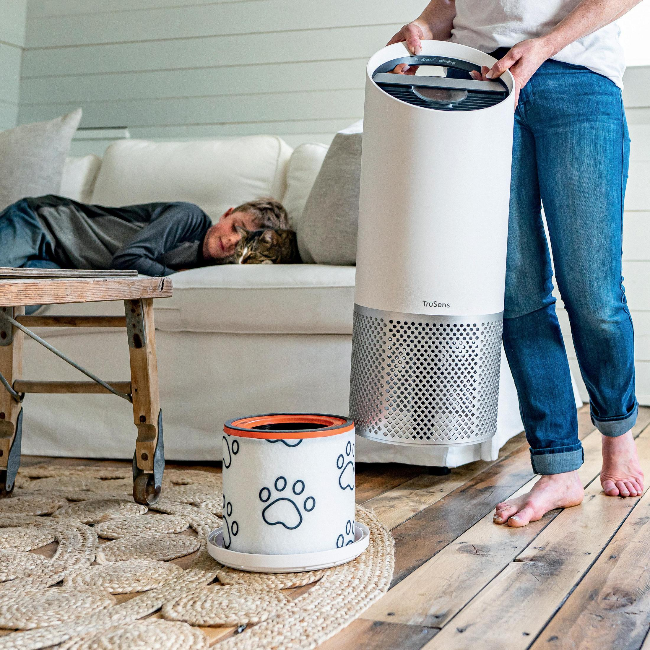 Osoba trzyma oczyszczacz powietrza. Śpiąca osoba i filtr na pierwszym planie.