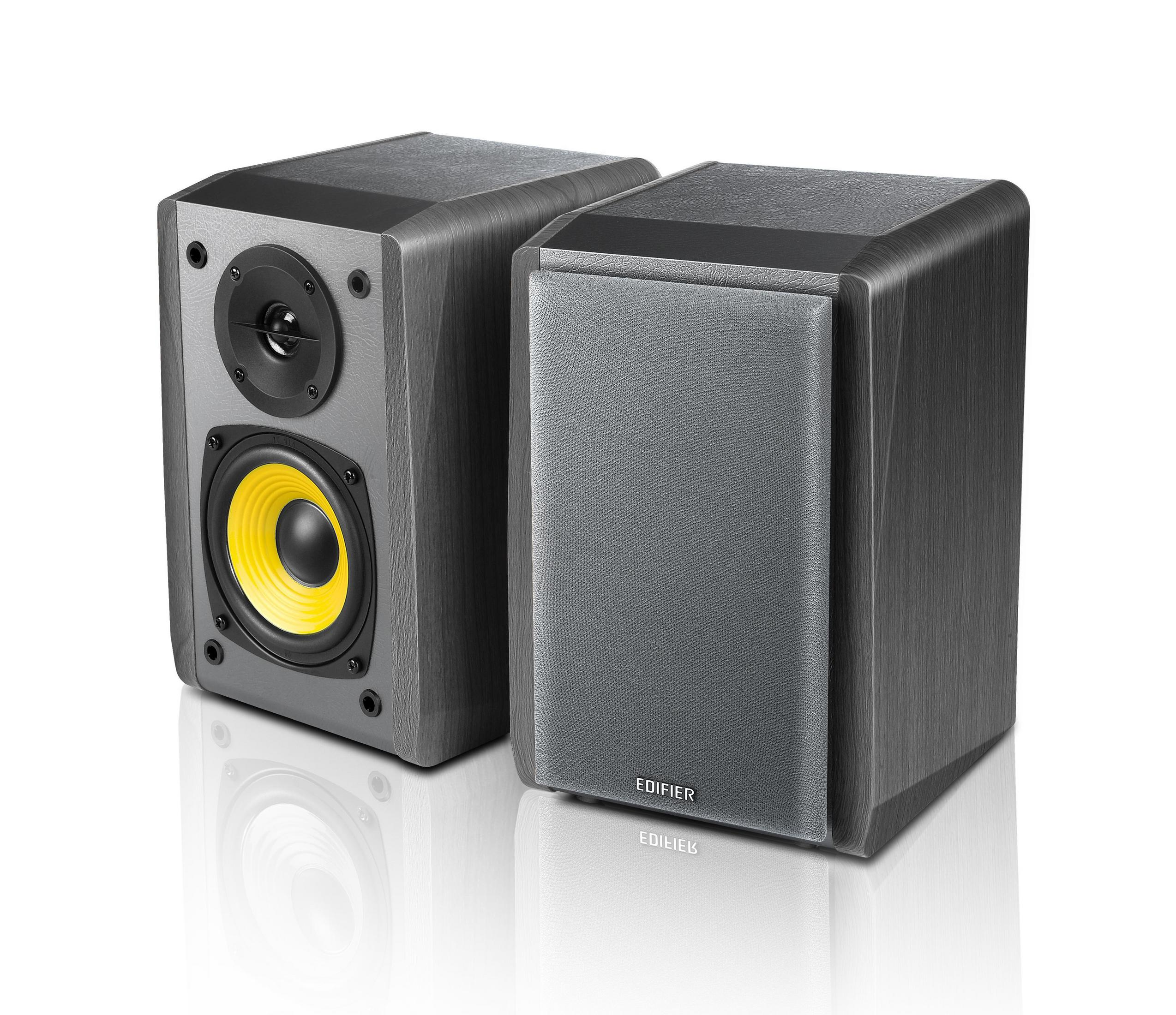 Dwa szare głośniki z żółtymi stożkami. Jeden głośnik jest skierowany w lewo, a drugi w prawo.