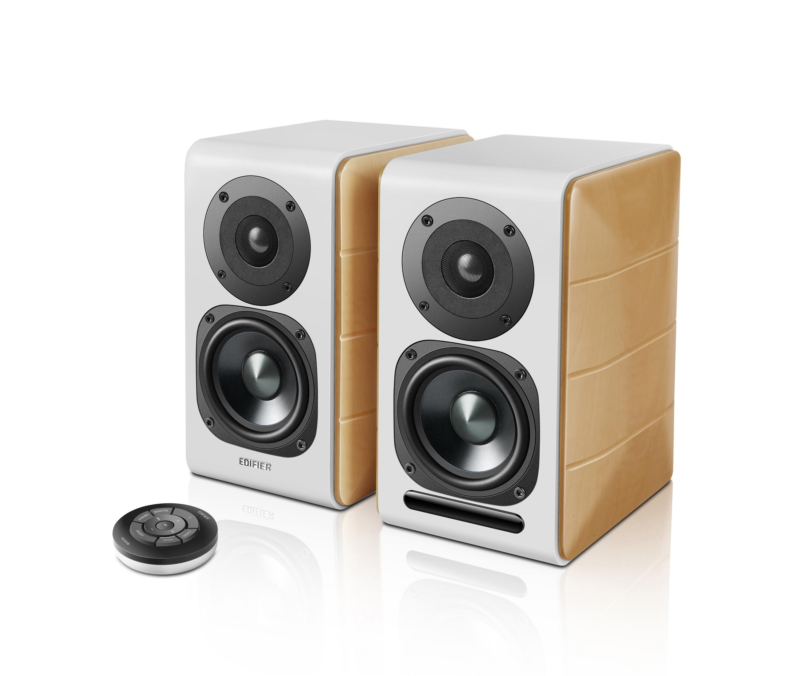 Dwa białe i drewniane głośniki. Czarne elementy sterujące. Białe tło.