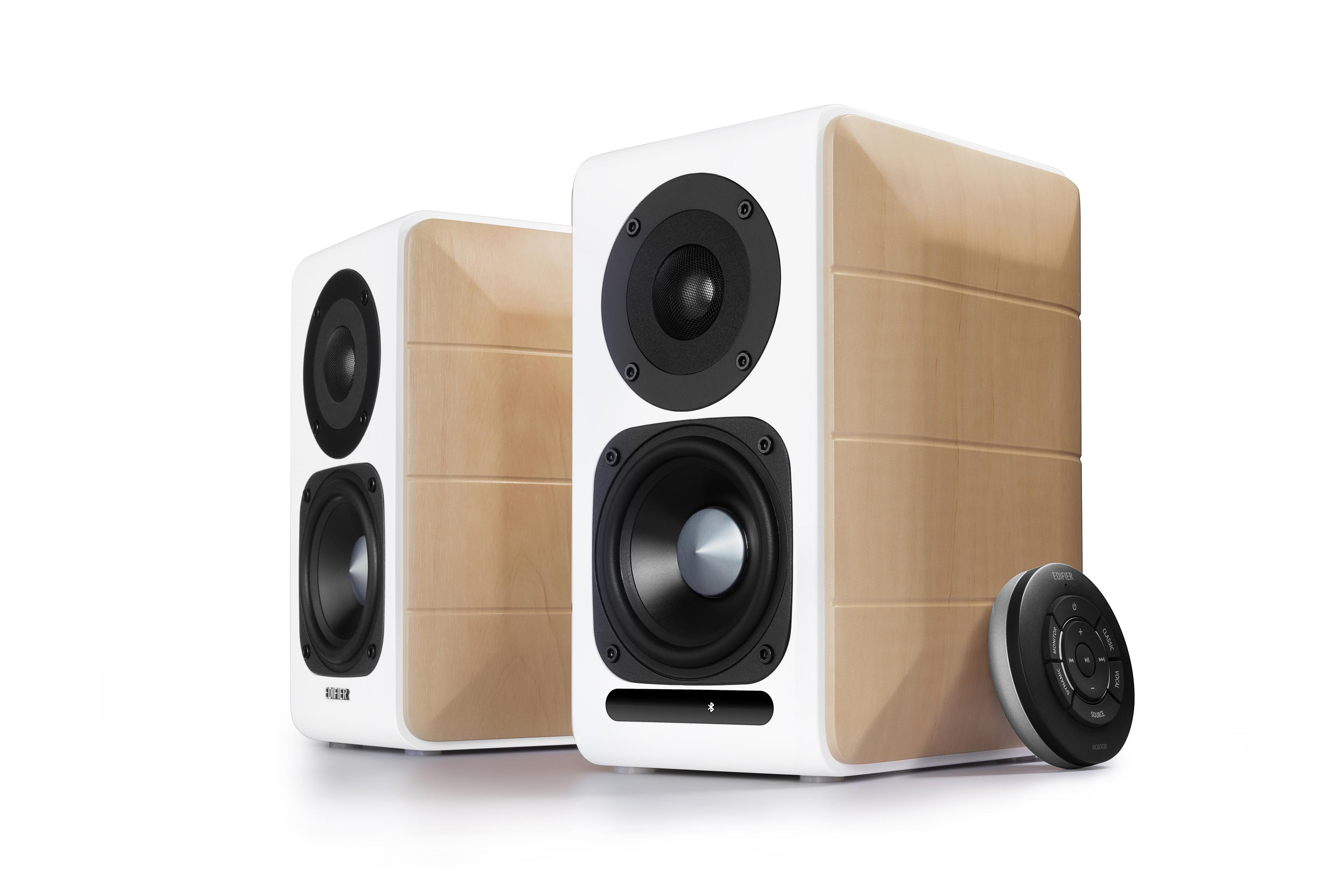 Dwa drewniane i białe głośniki z czarnymi membranami i pilotem.