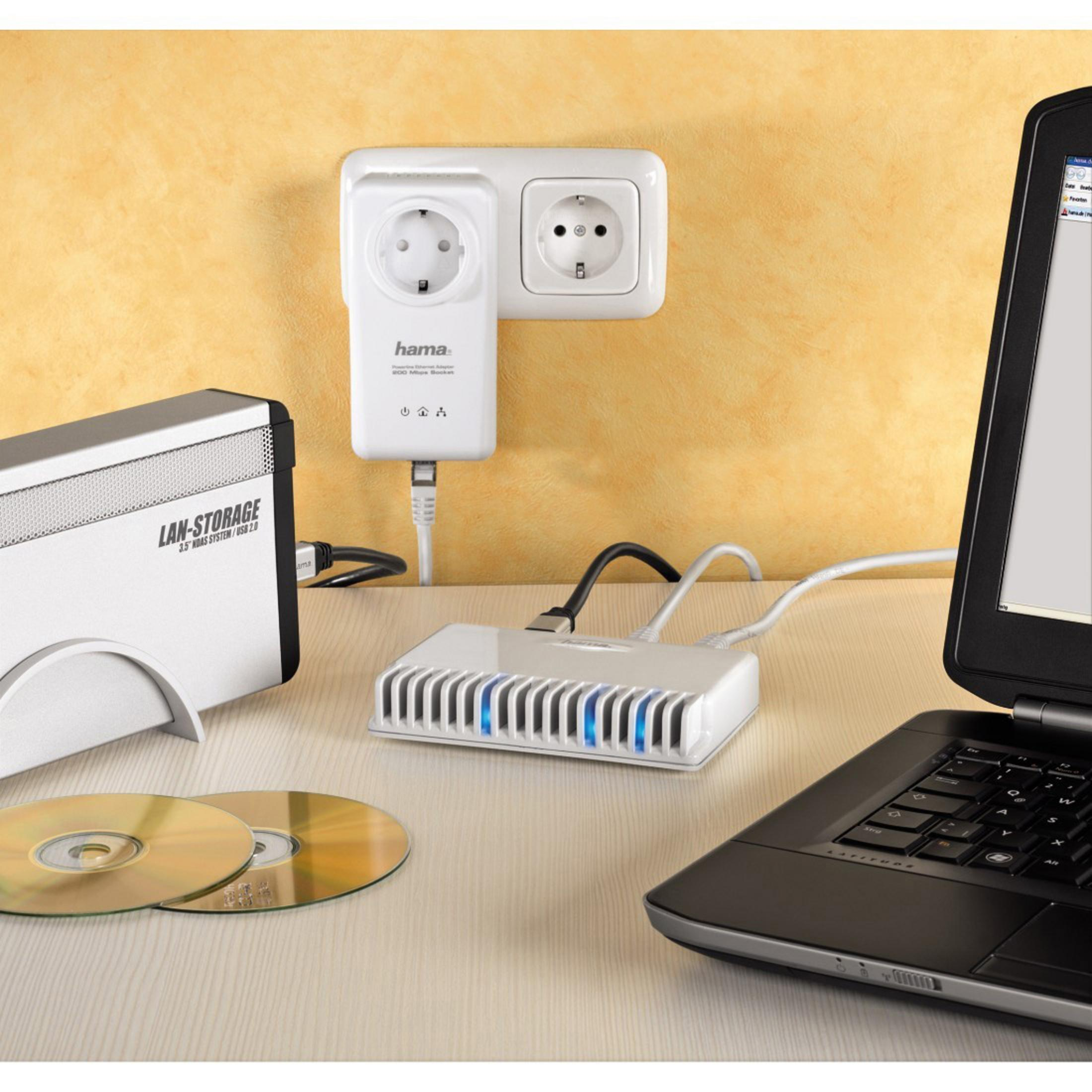 Schreibtisch mit Laptop, Router und CDs. Gelber Wandhintergrund.