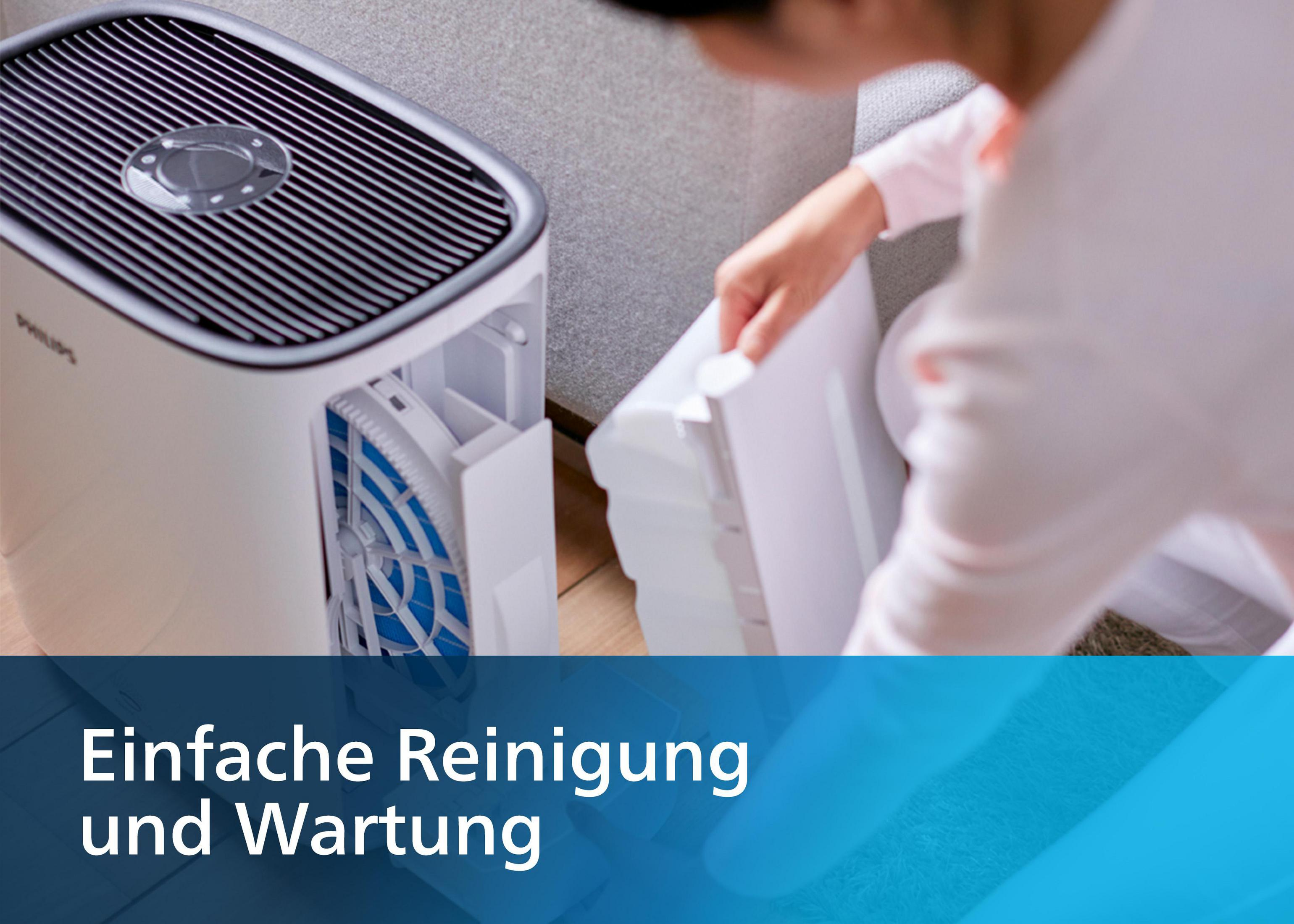 Persona rimuove il filtro dal purificatore d'aria. Apparecchio bianco e nero su pavimento in legno.