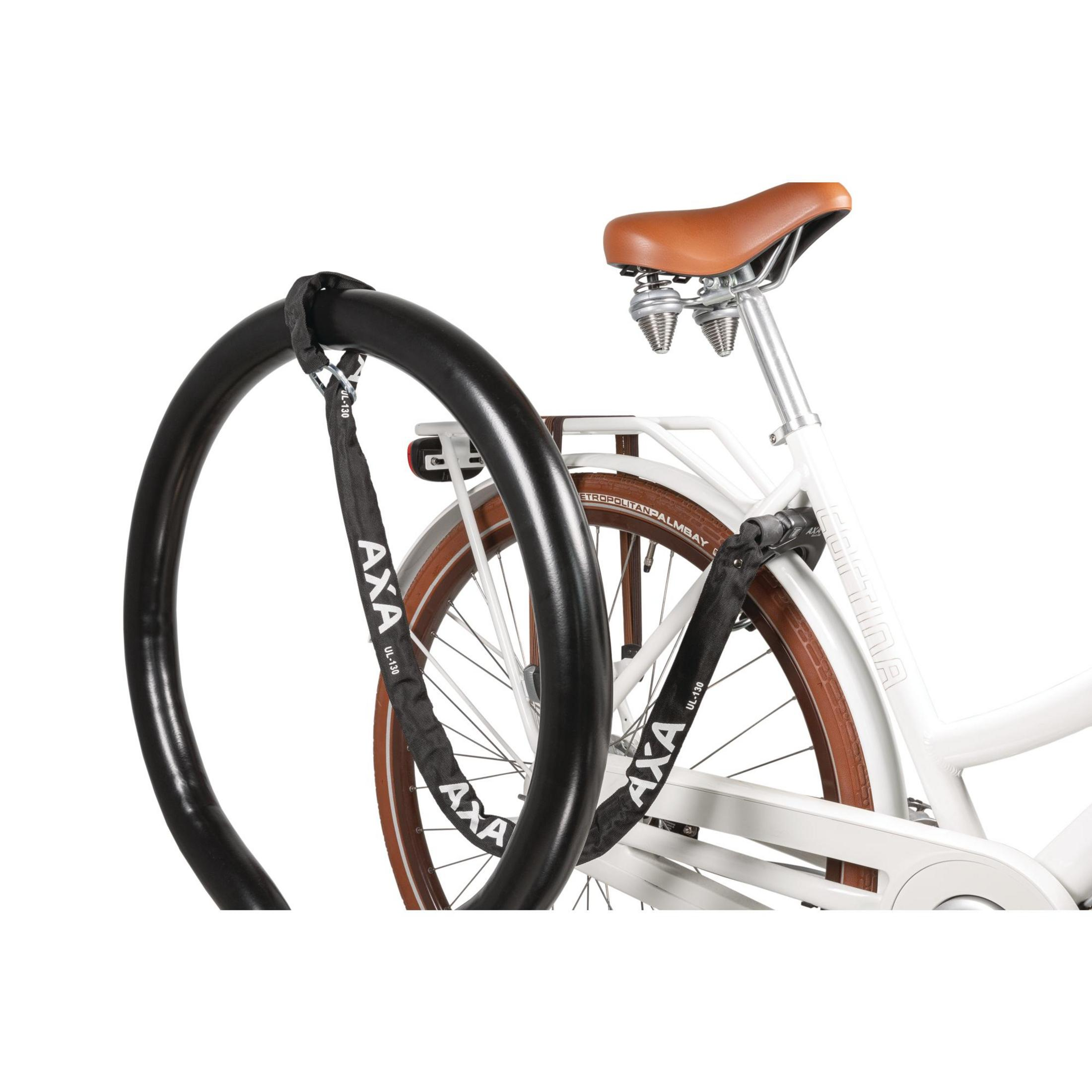 Biały rower przypięty do czarnego stojaka na rowery za pomocą czarnej blokady.