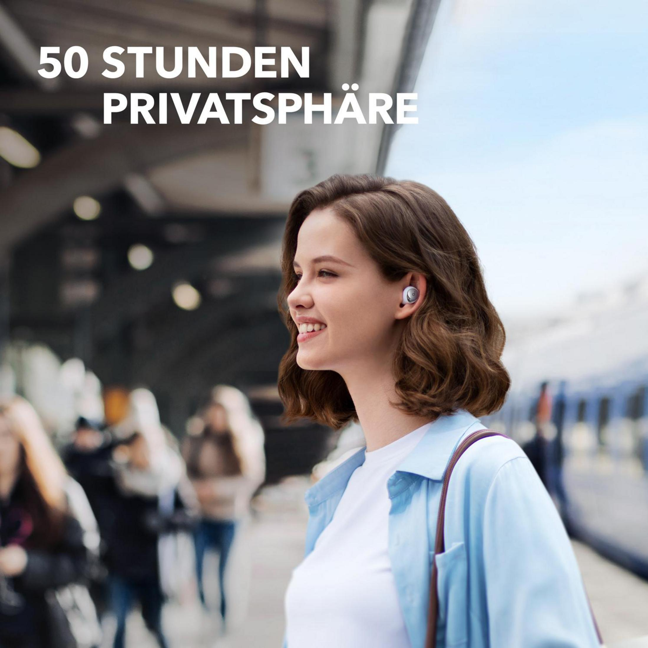 Eine lächelnde Frau mit Ohrhörern auf einem Bahnsteig. Text auf Deutsch: '50 Stunden Privatsphäre'.