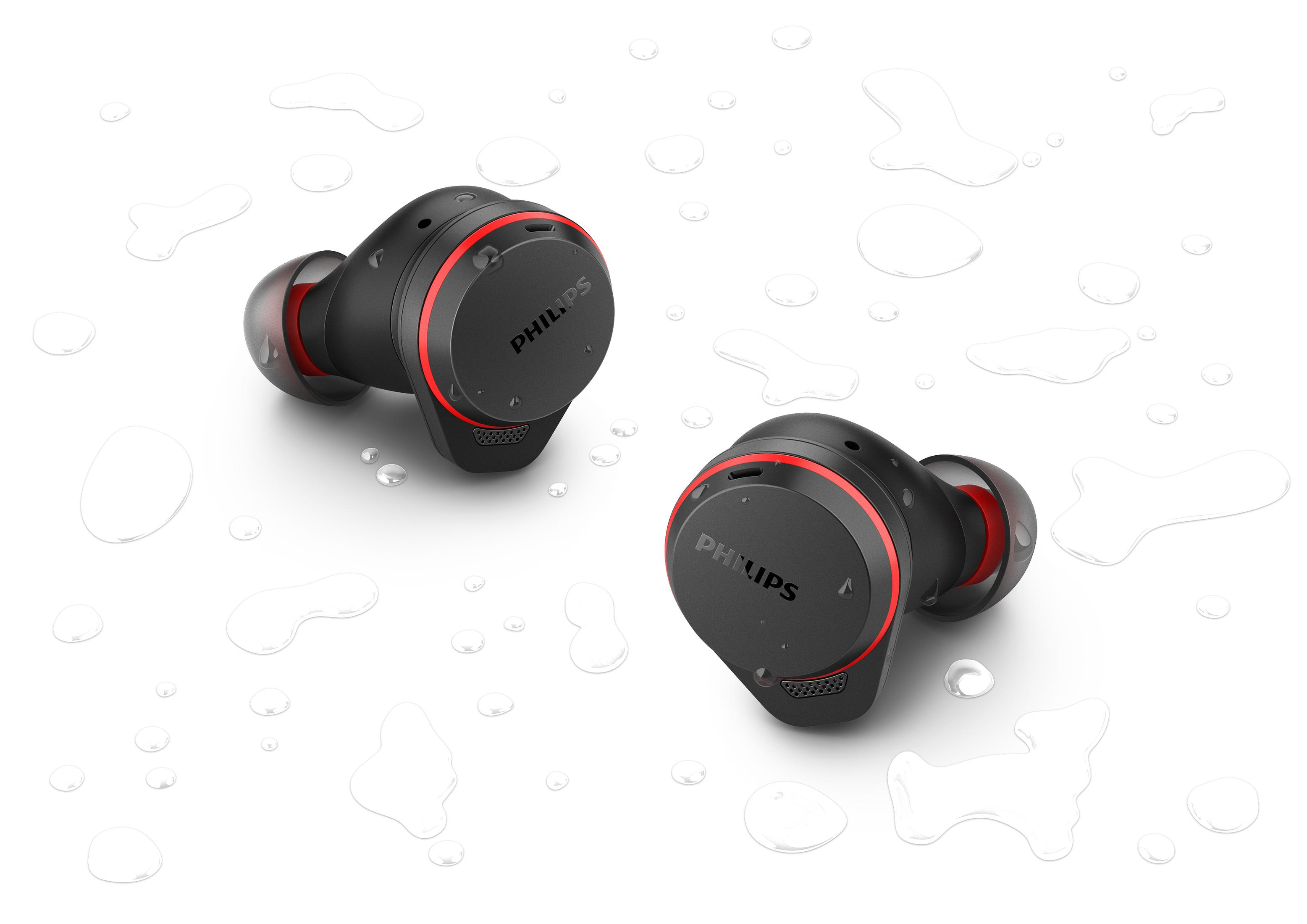 Para czarnych i czerwonych bezprzewodowych słuchawek Philips. Leżą na białej powierzchni z kroplami wody.