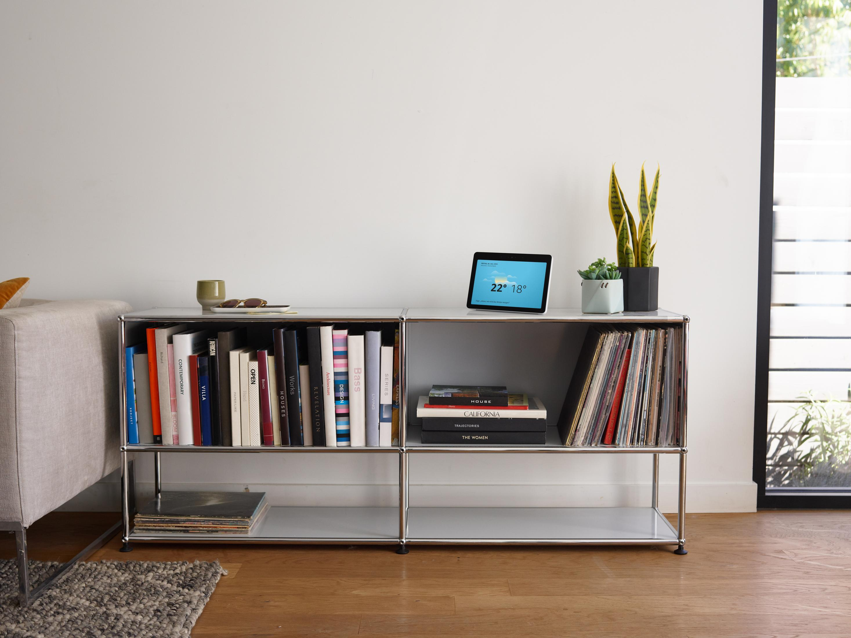 Modernes Wohnzimmer mit Bücherregal, Smart Display und Fenster.