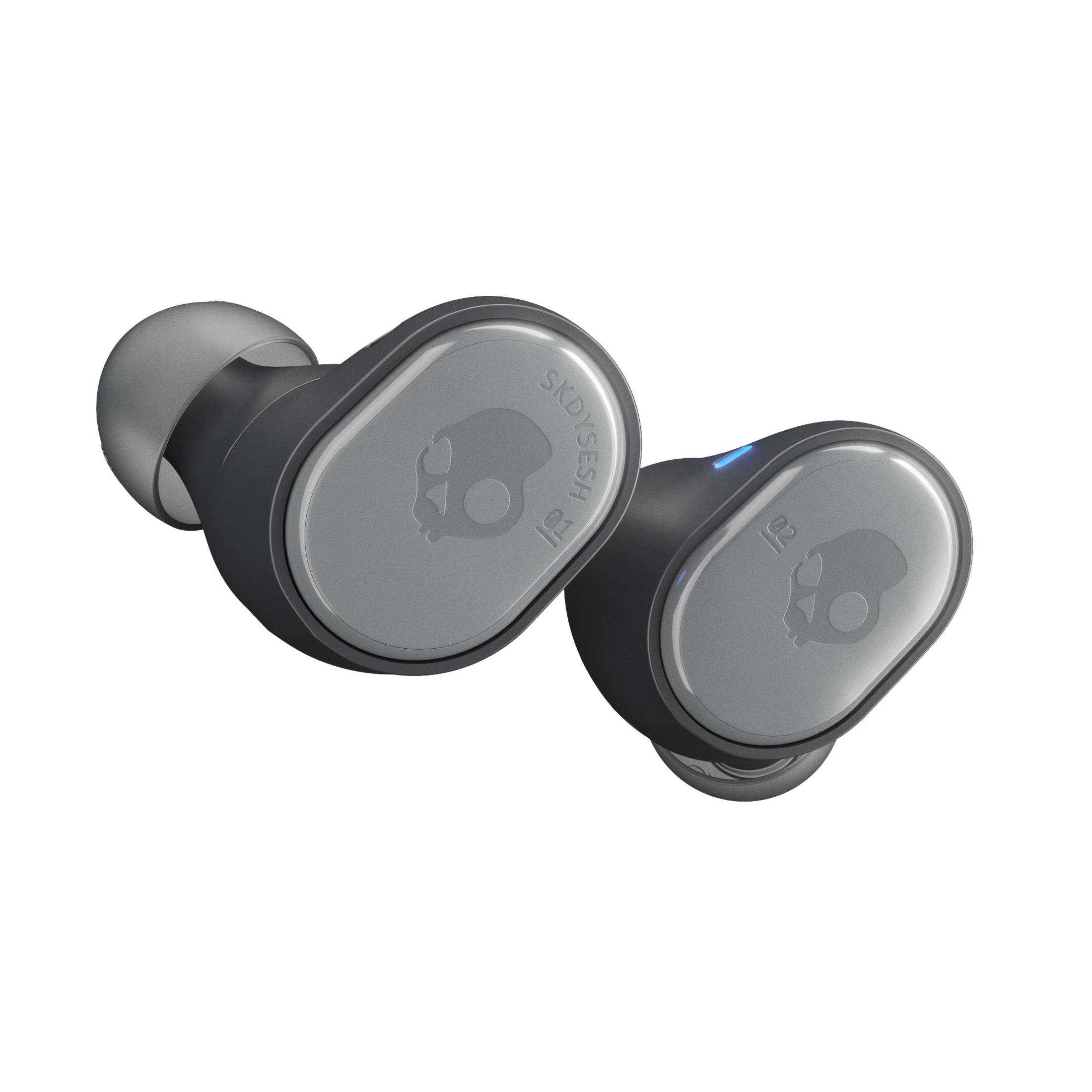 Para szarych słuchawek Skullcandy. Każda słuchawka ma szarą płytkę czołową z logo czaszki.