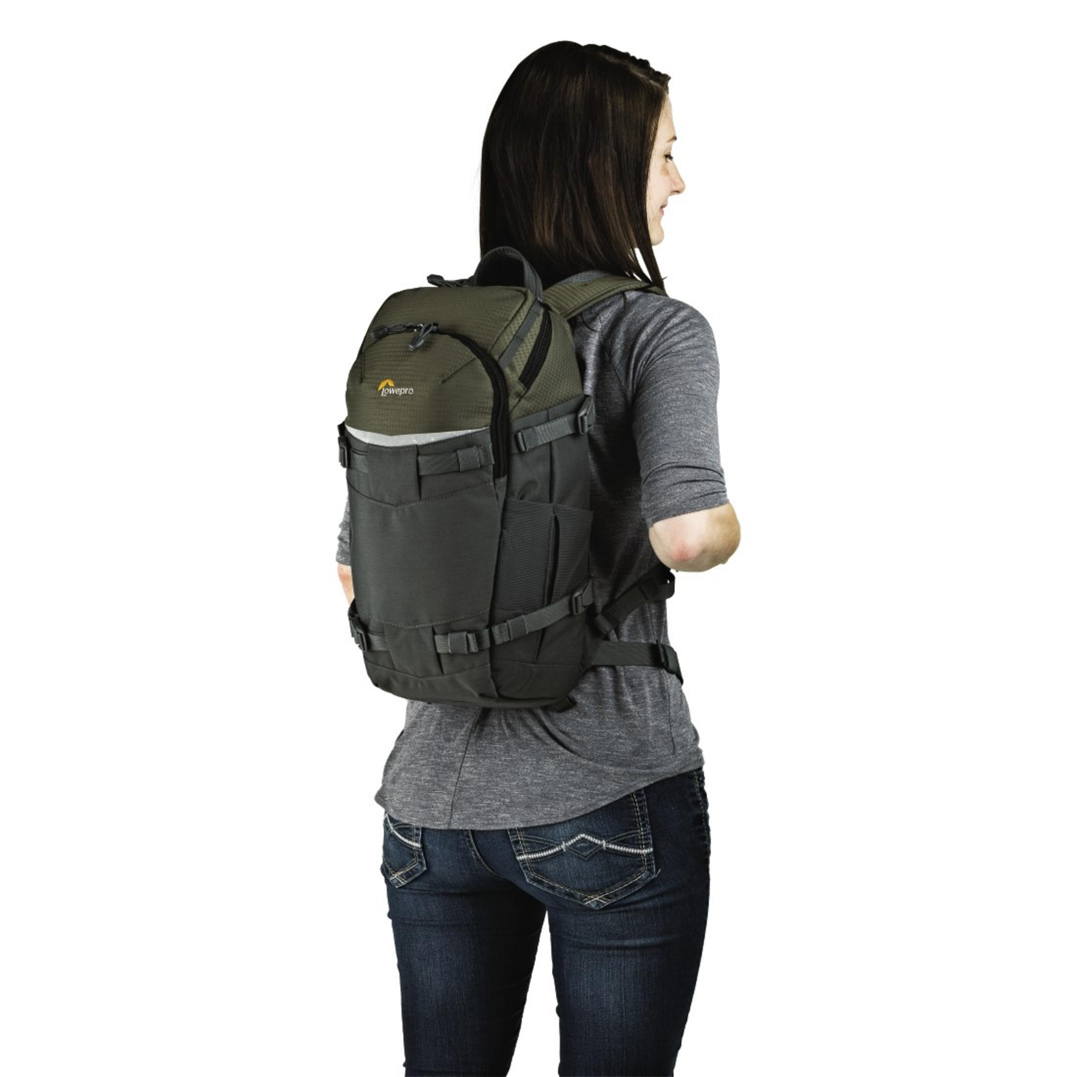 Femme en chemise grise et jean avec sac à dos Lowepro noir et vert.