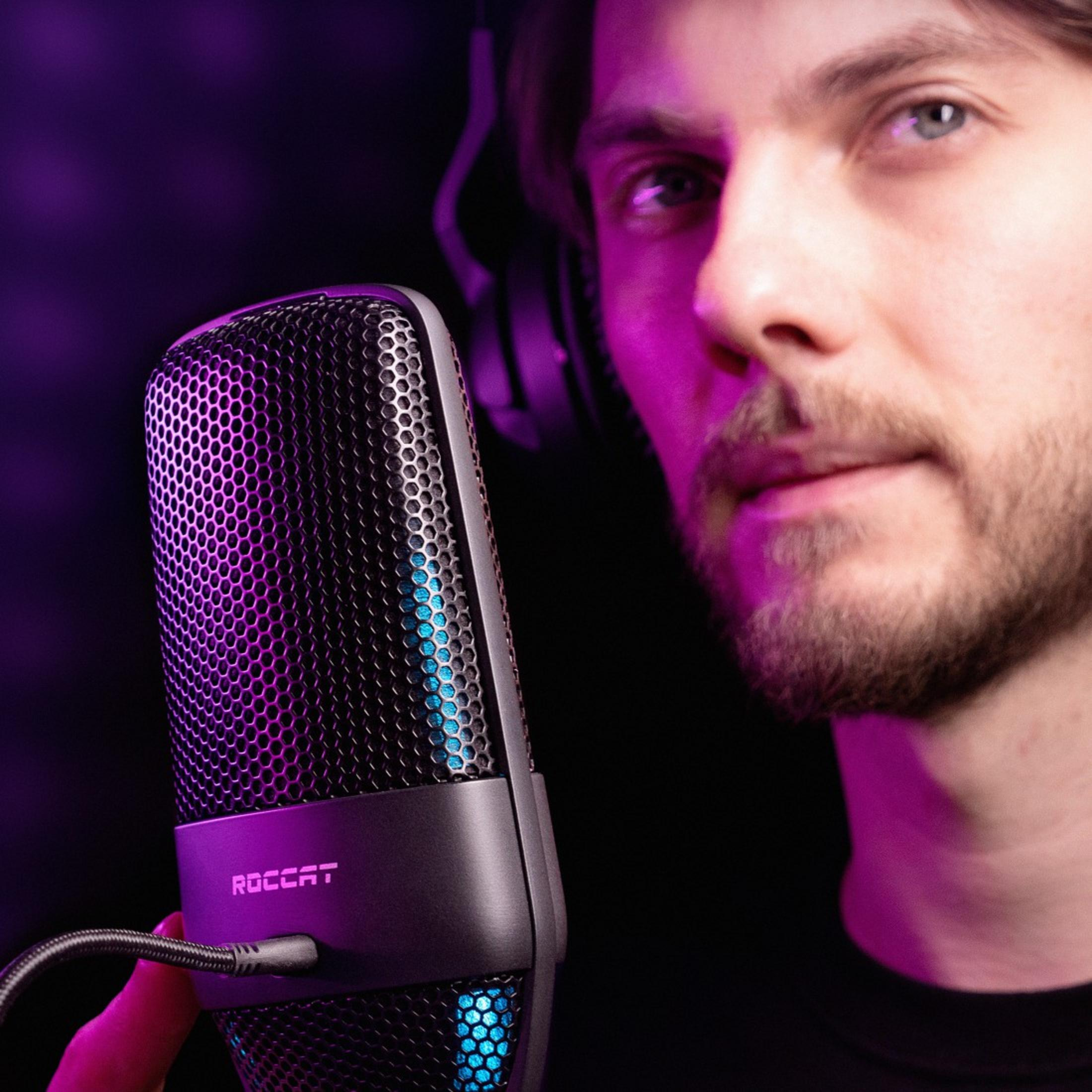 Ein Mann hält ein schwarzes Mikrofon mit dem 'ROCCAT'-Logo.