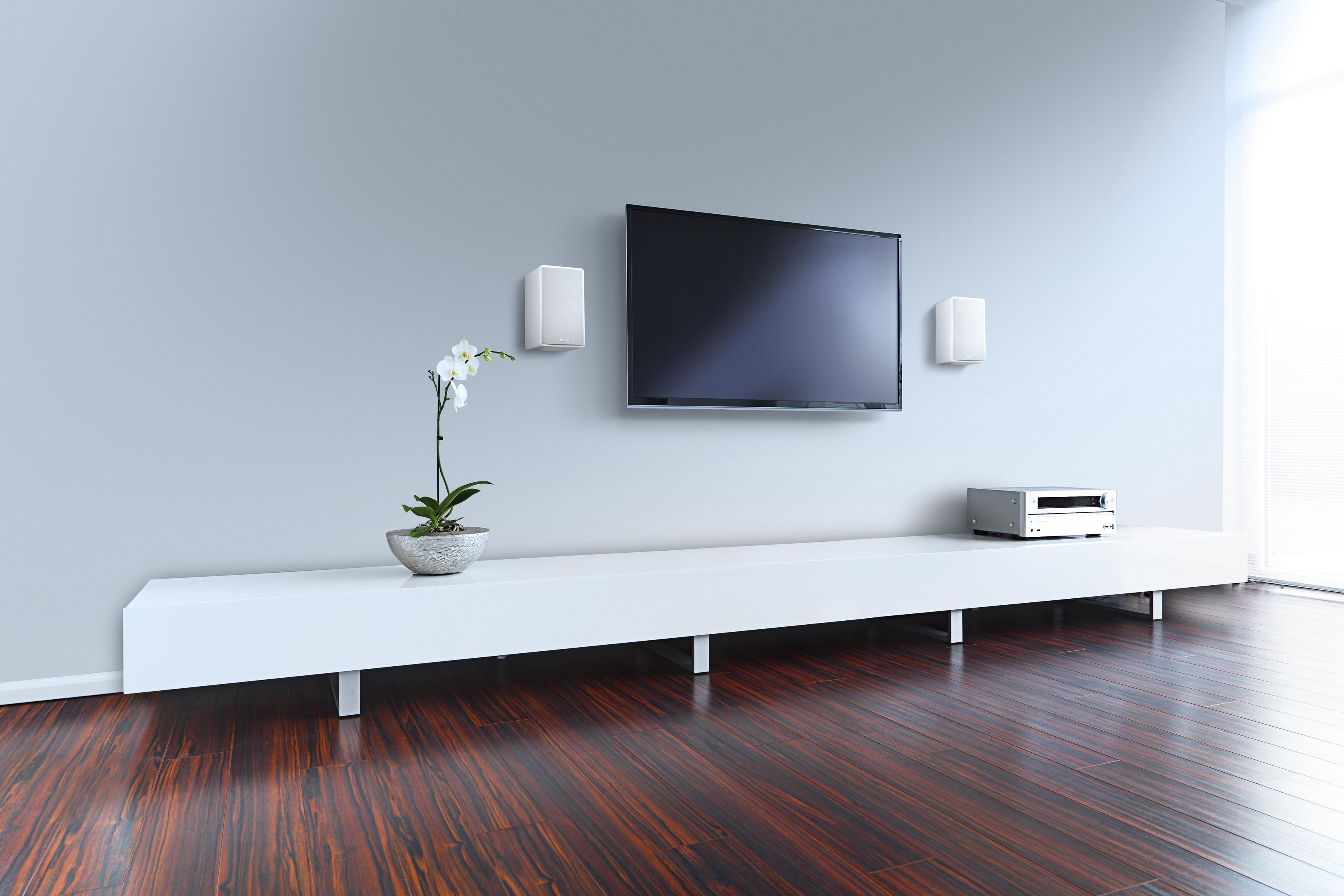 Wohnzimmer mit Fernseher, Lautsprechern und einem weißen Unterhaltungscenter. Holzboden.