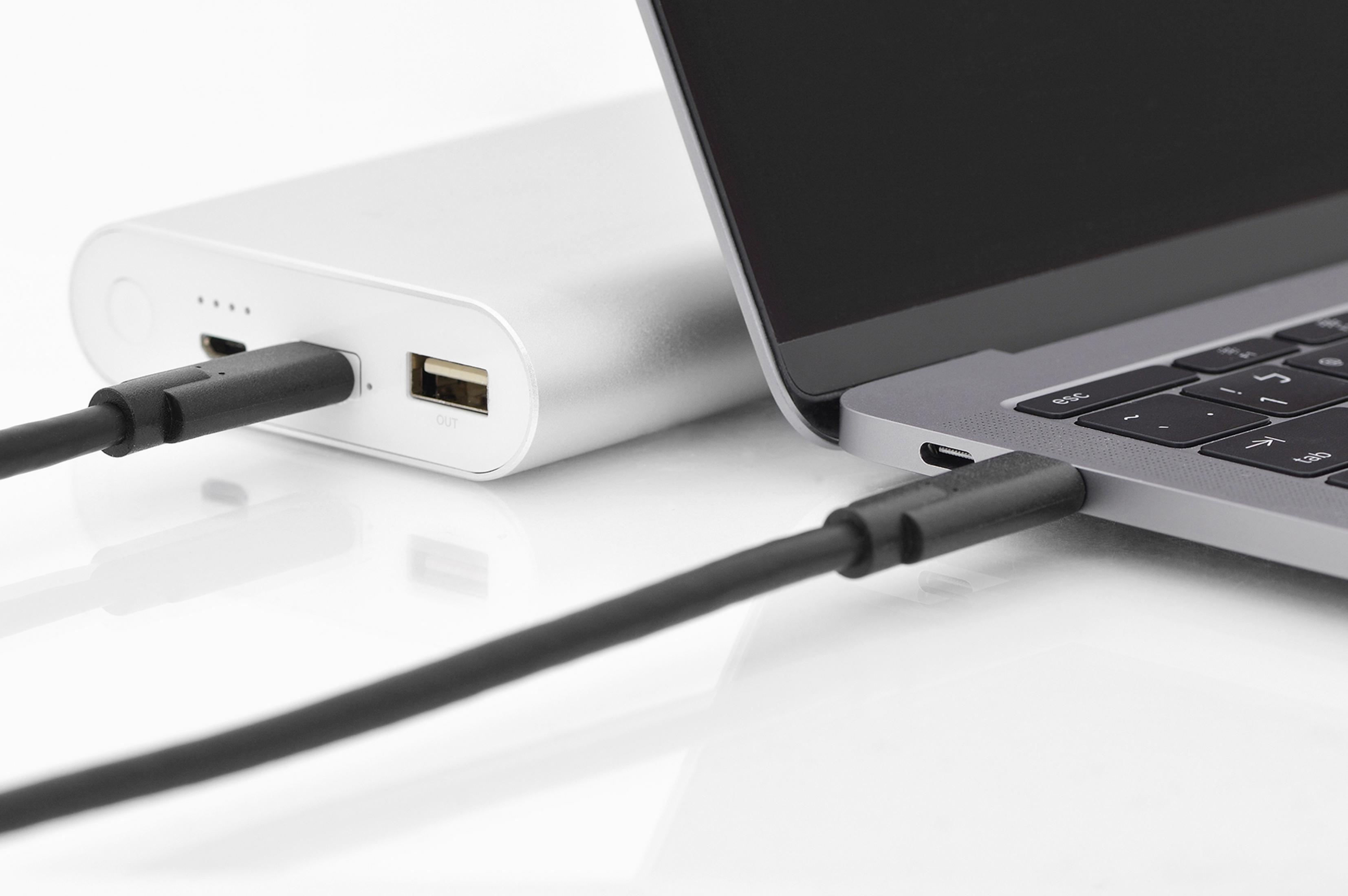 Ordinateur portable connecté à une batterie externe via câble USB-C, blanc.