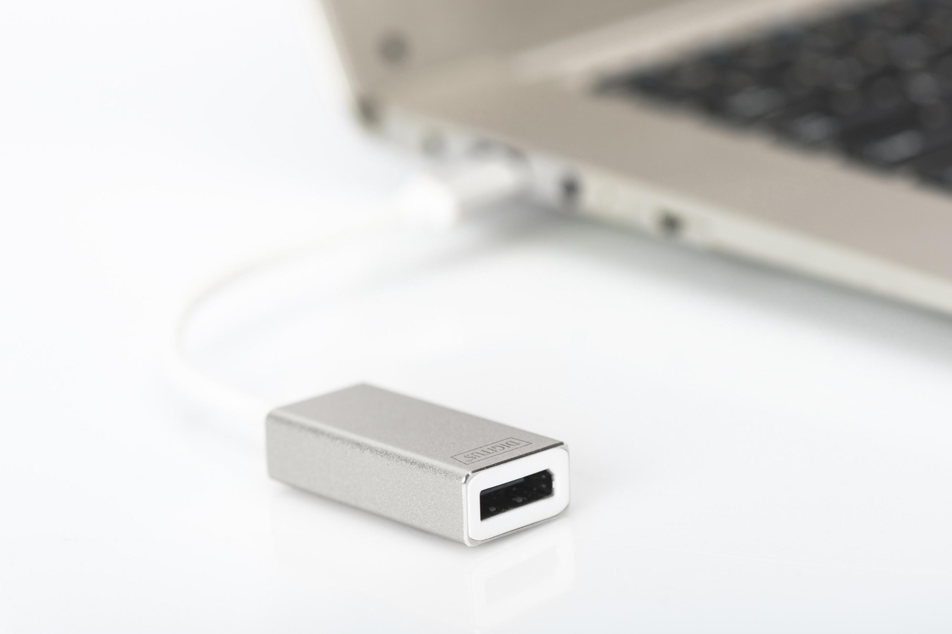 Ein silberner USB-Adapter, der an einen Laptop angeschlossen ist. Weißes Kabel.