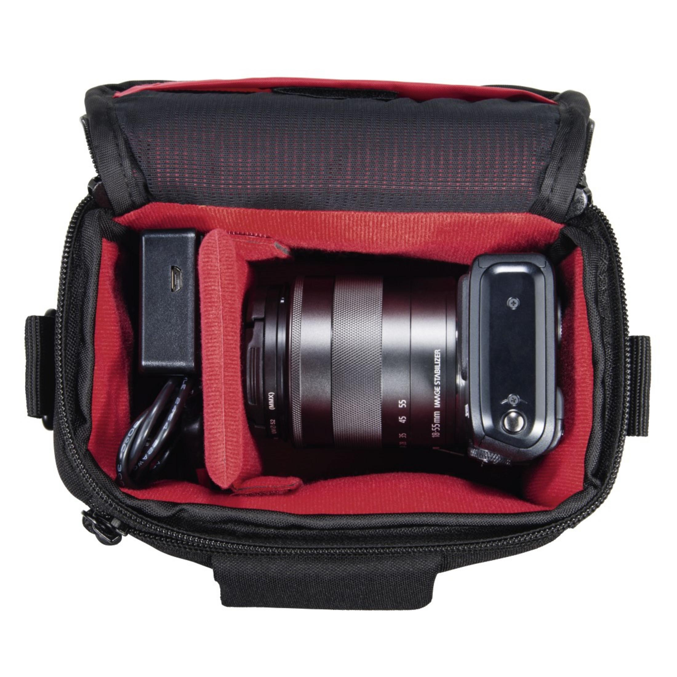 Kamera und Zubehör in einer schwarzen Tasche mit roter Innenausstattung.