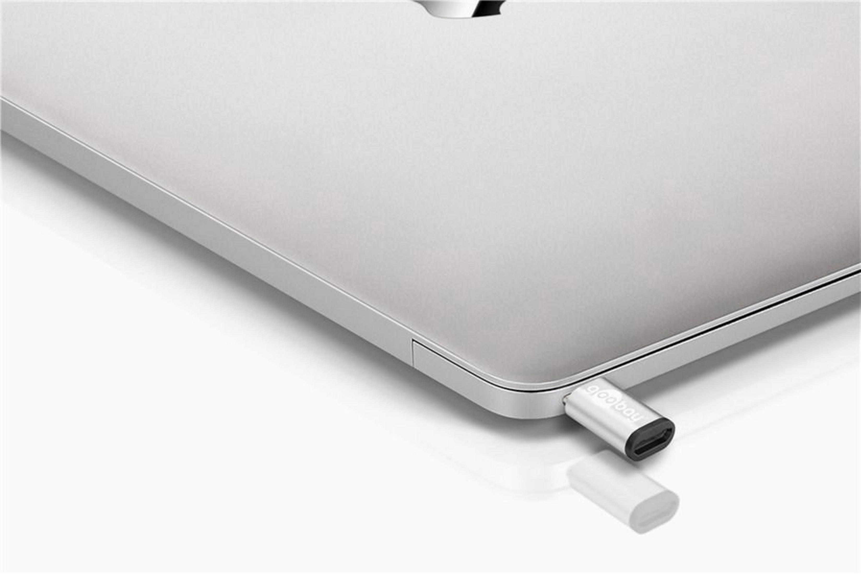 Srebrny adapter USB-C podłączony do srebrnego laptopa. Białe tło.