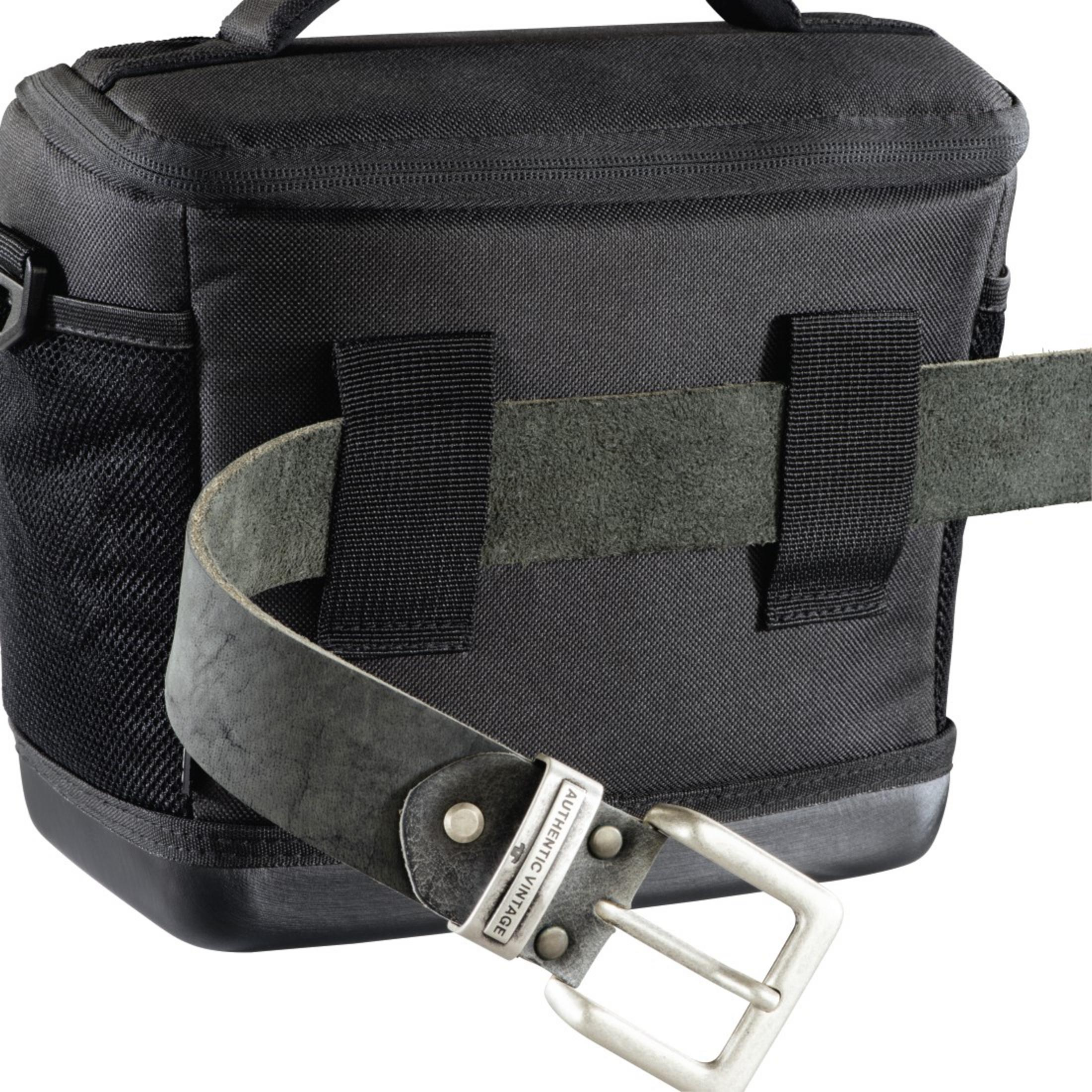 Czarna torba na aparat z czarnym skórzanym paskiem i srebrną klamrą. Pasek jest przymocowany do torby.