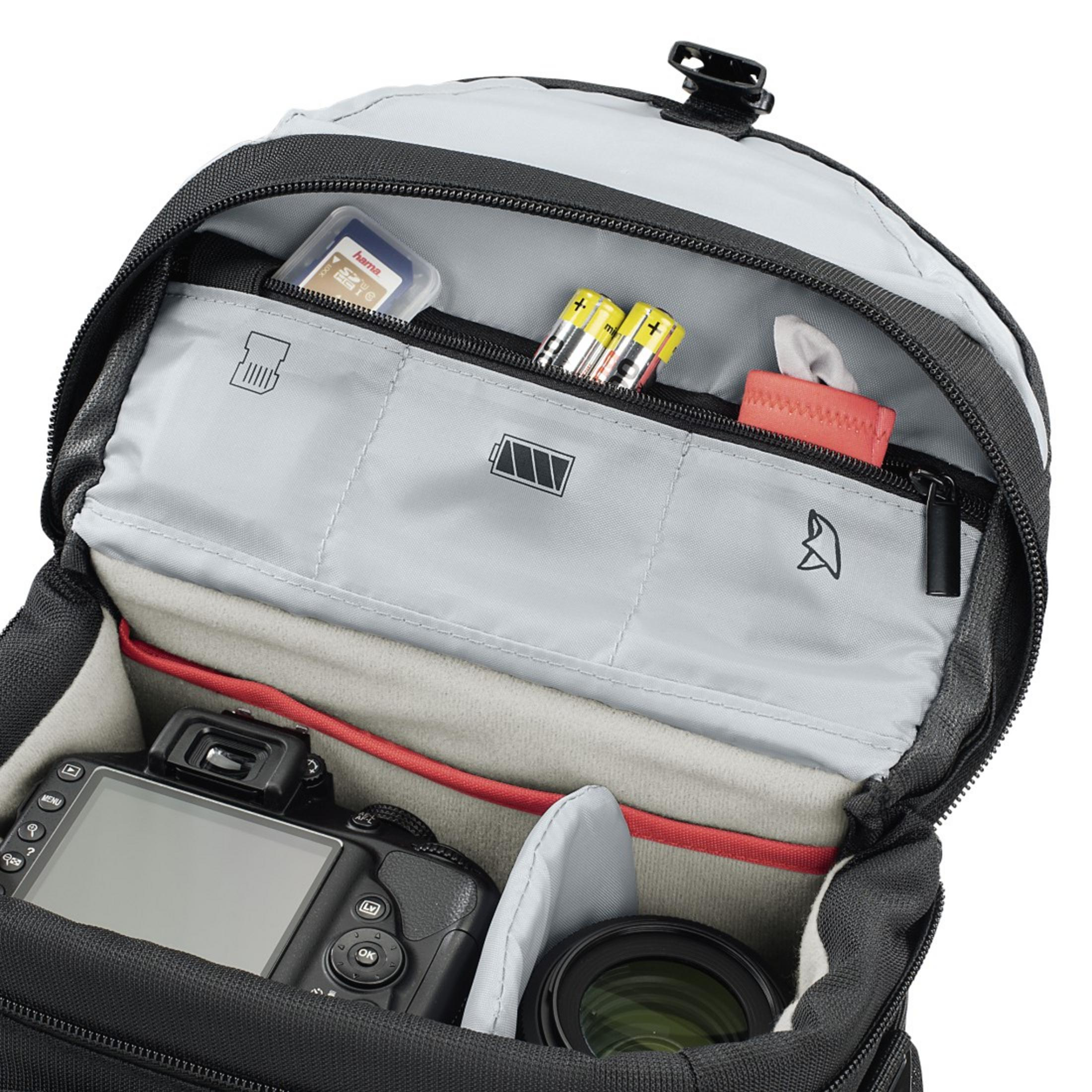 Eine Kameratasche geöffnet, mit Kamera, Objektiv, SD-Karte, Batterien und anderem Zubehör.