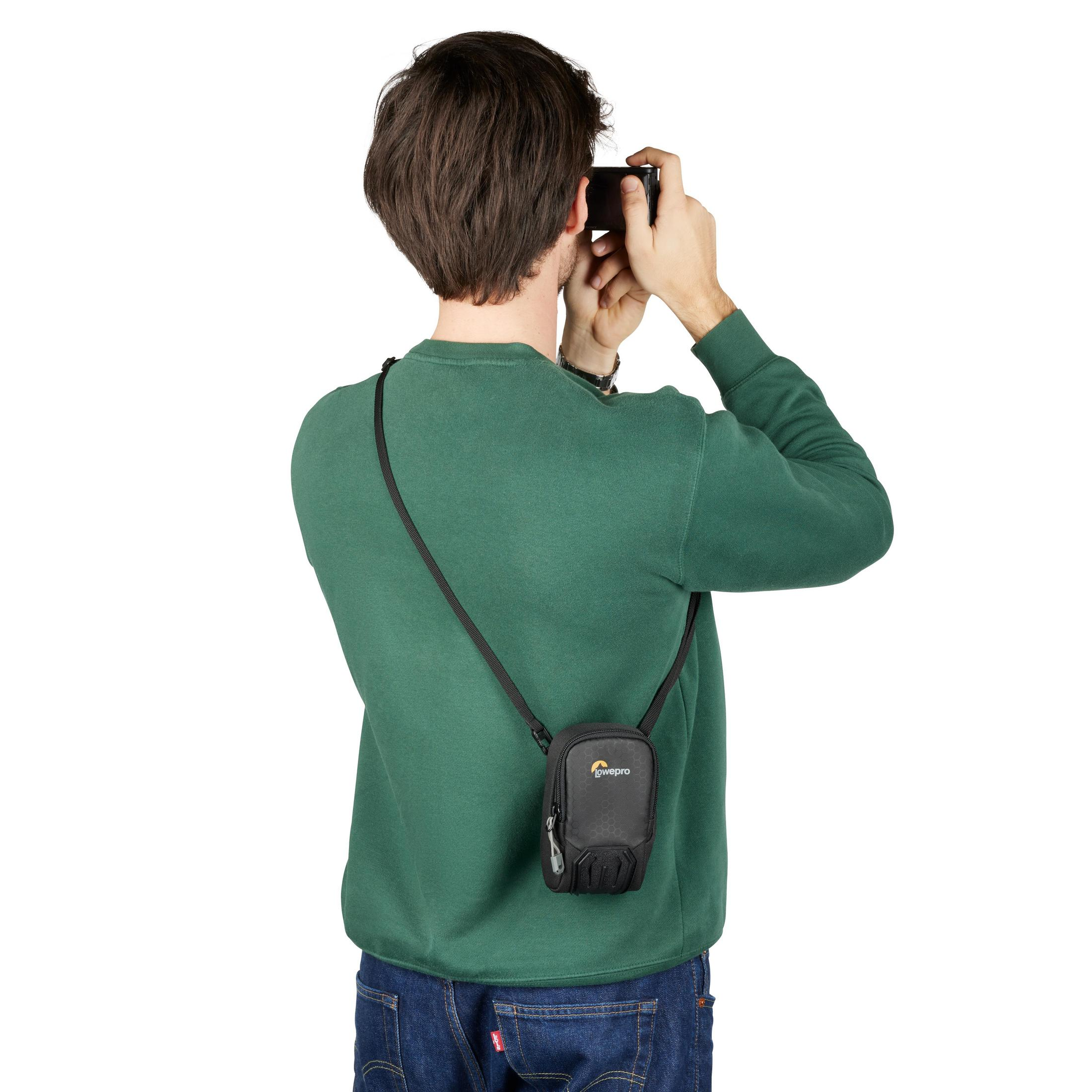 Person fotografiert mit einem Telefon. Das Telefon ist in einer kleinen schwarzen Tasche.
