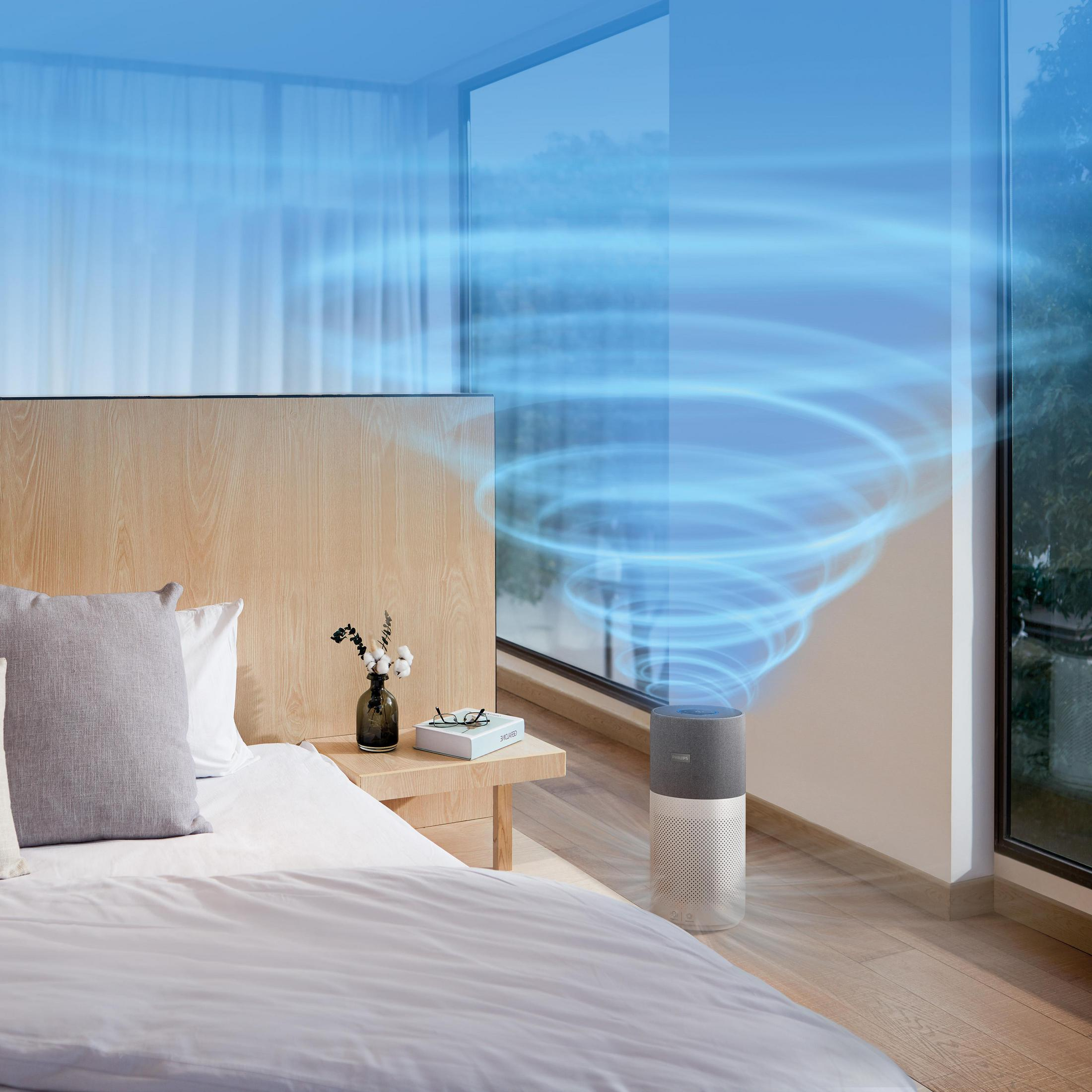 Purificatore d'aria in una stanza con finestra e letto. Un vortice azzurro è visibile.