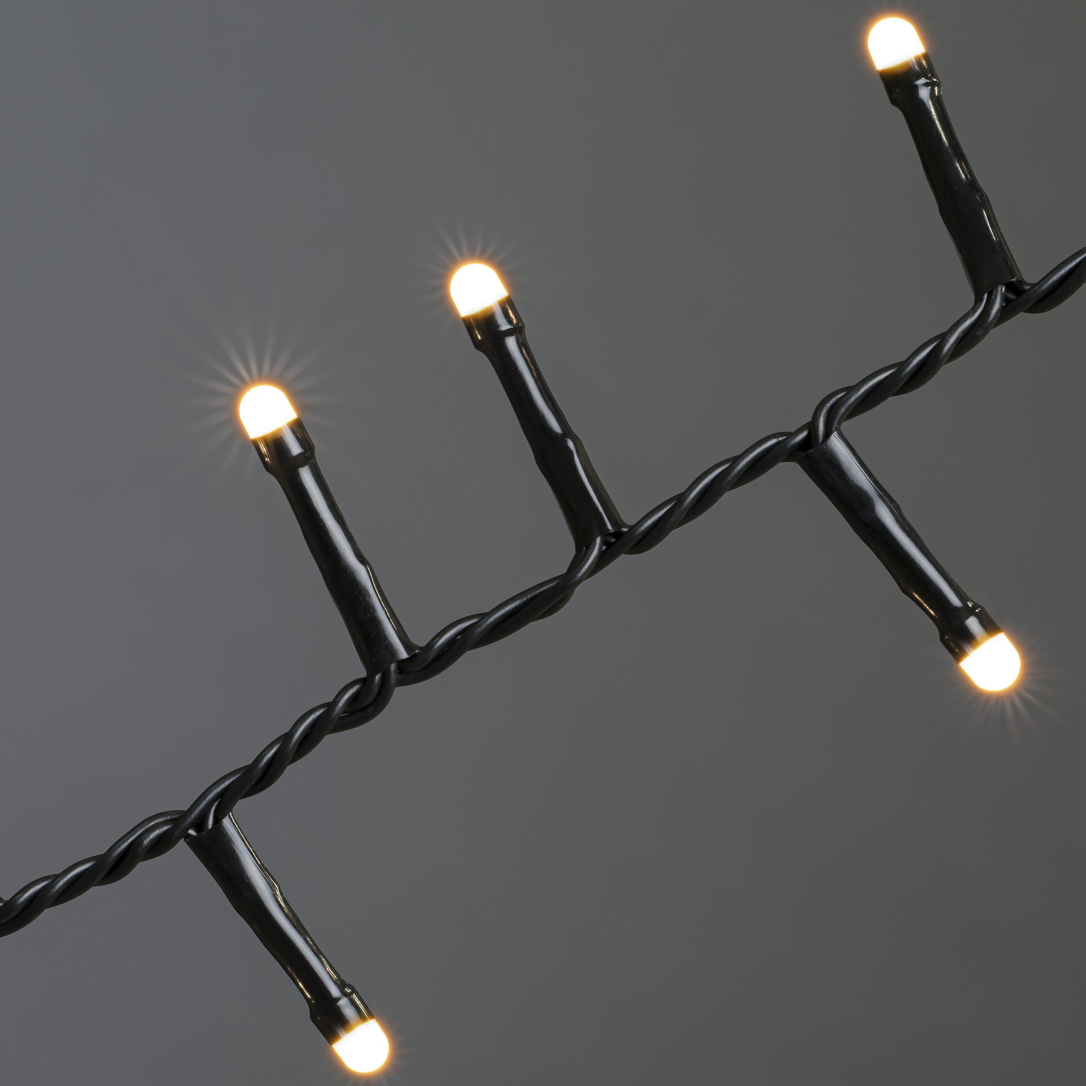 Nahaufnahme eines schwarzen, verdrillten Drahtes mit fünf kleinen, hellen Lichtern.